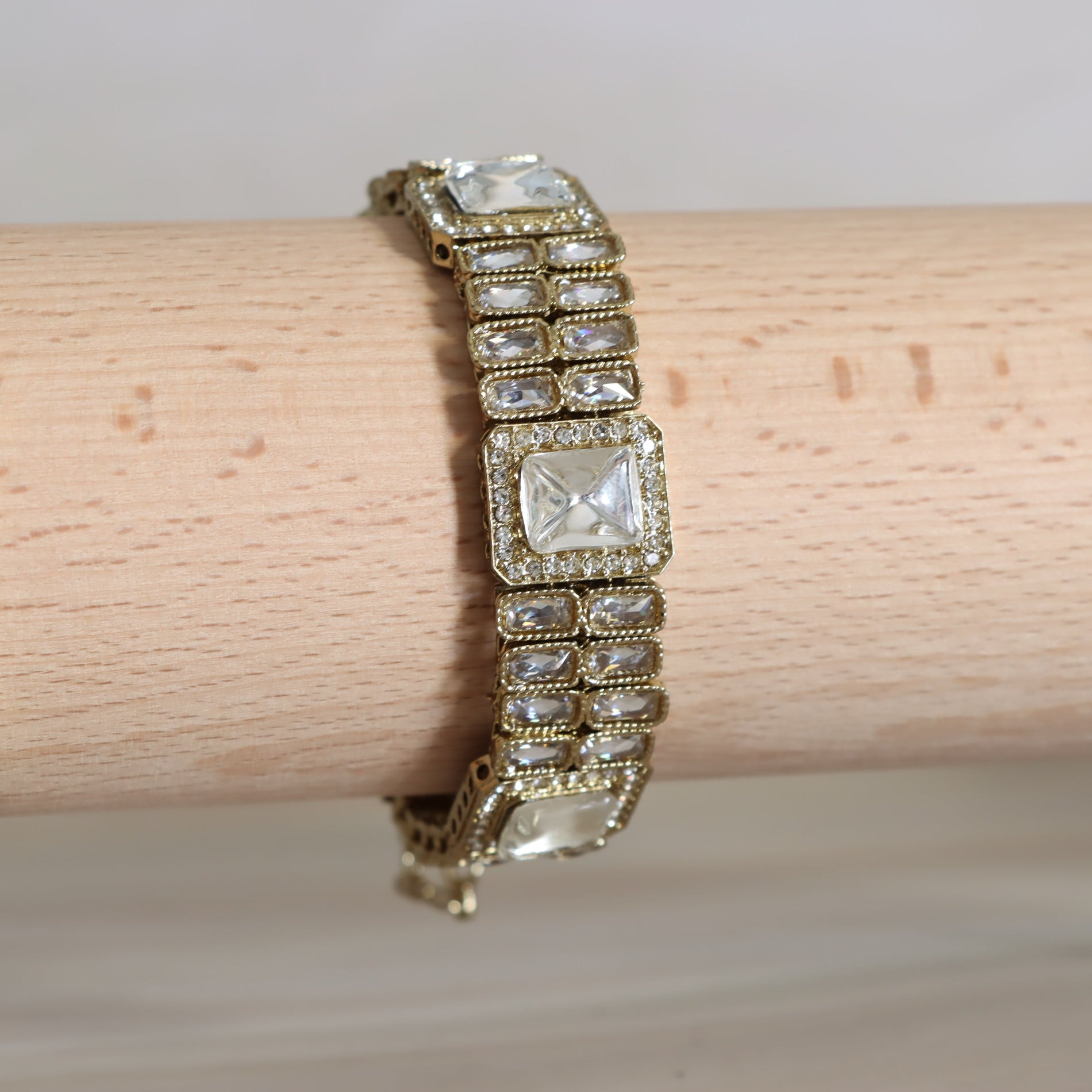 Gold bracelet with clear gemstones on a wooden surface