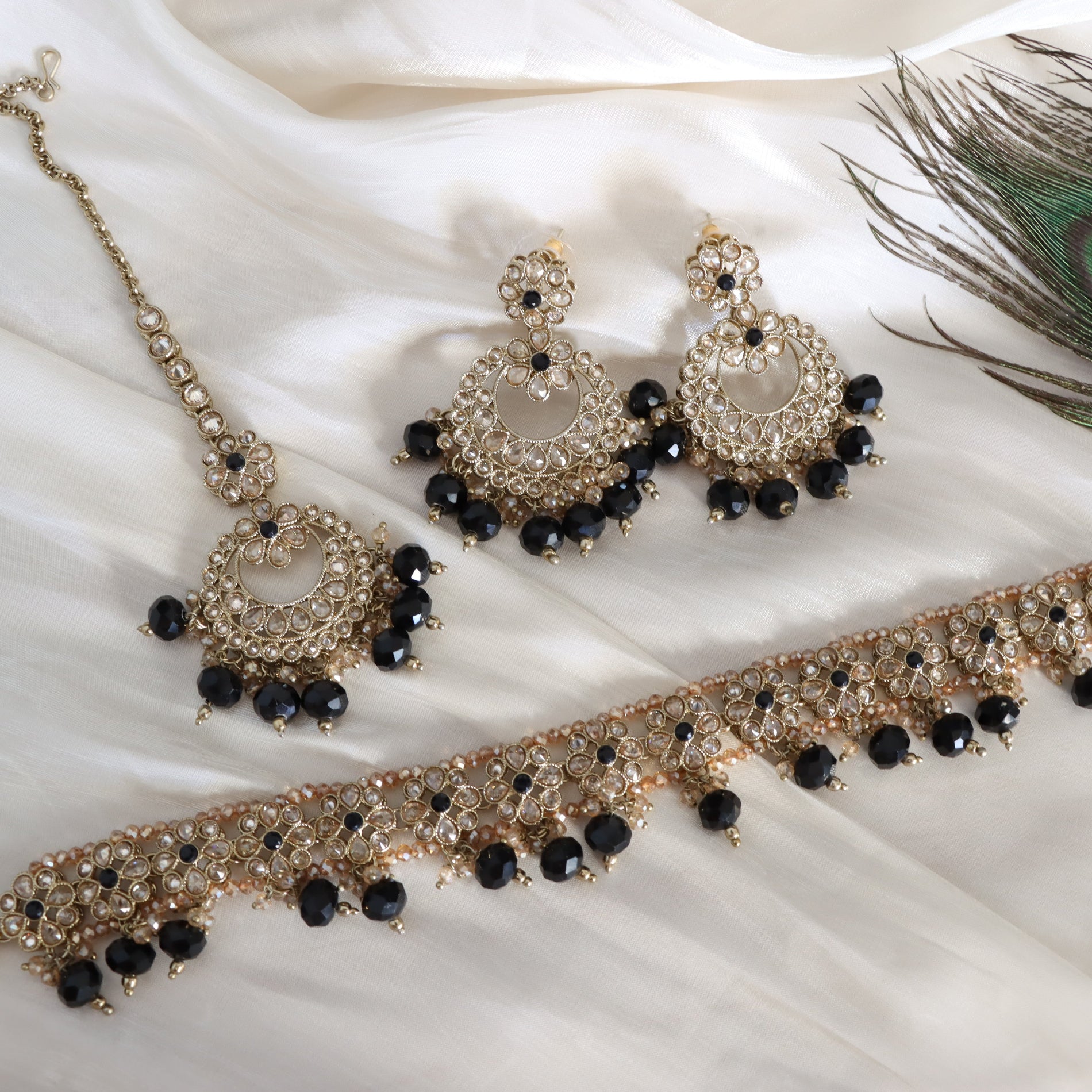 Jewelry set with necklace, earrings, and choker on a white fabric background