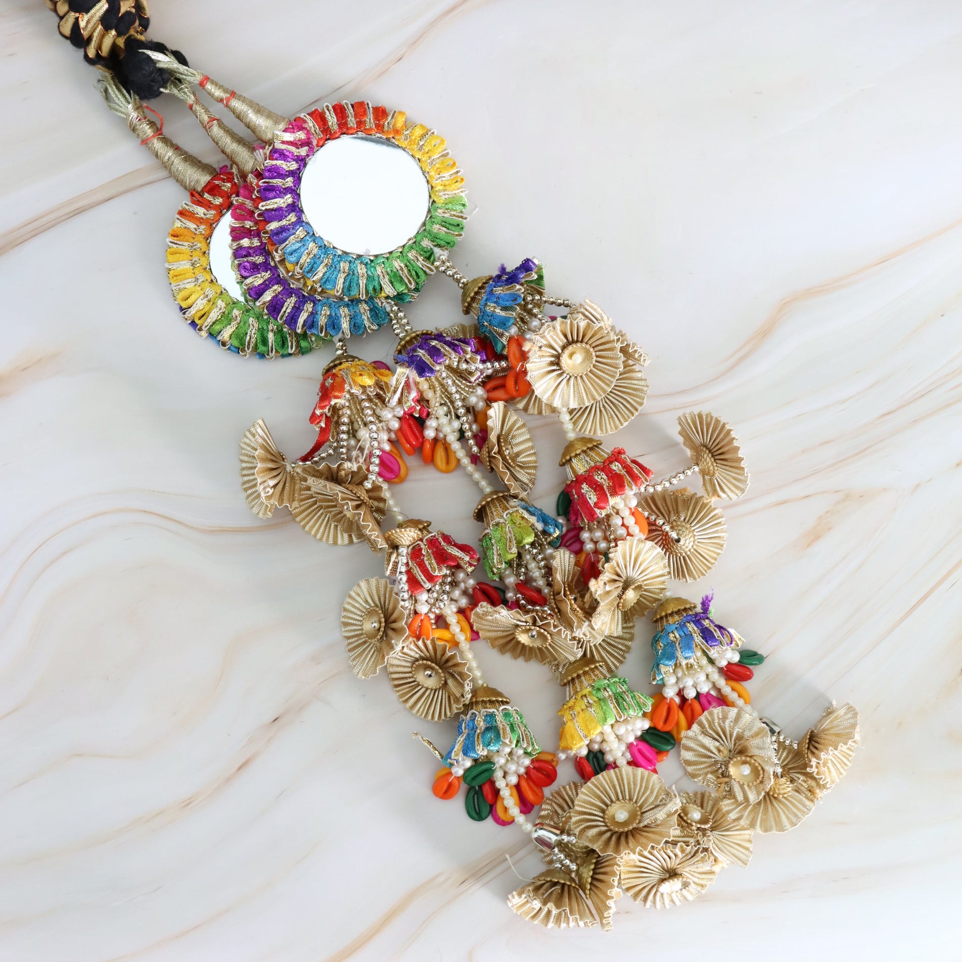 Colorful beaded mirror with gold accents on a marble surface