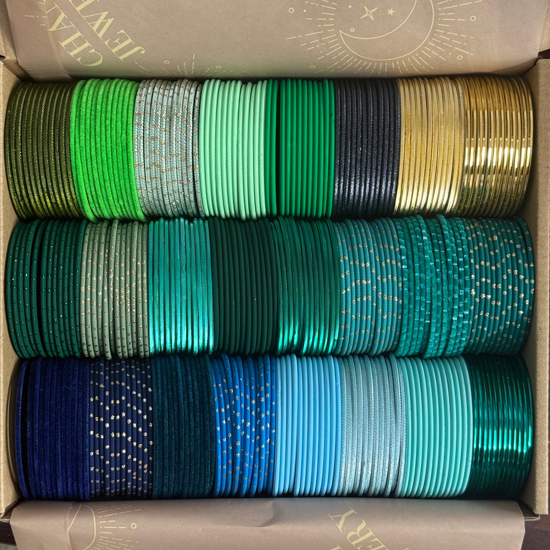 Box containing multiple rolls of green, blue, and gold bangles