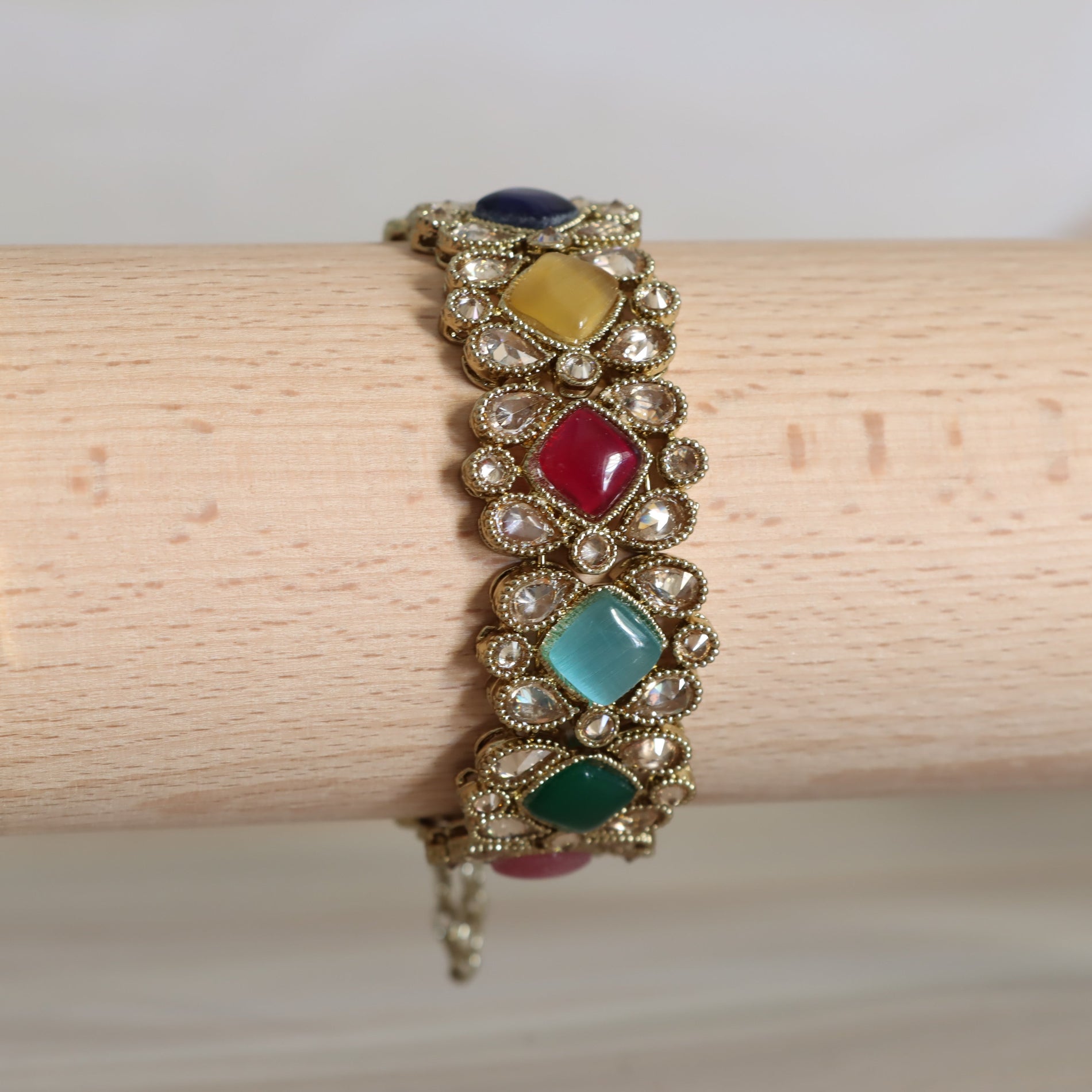 Multicolored gemstone bracelet on a wooden stick against a white background