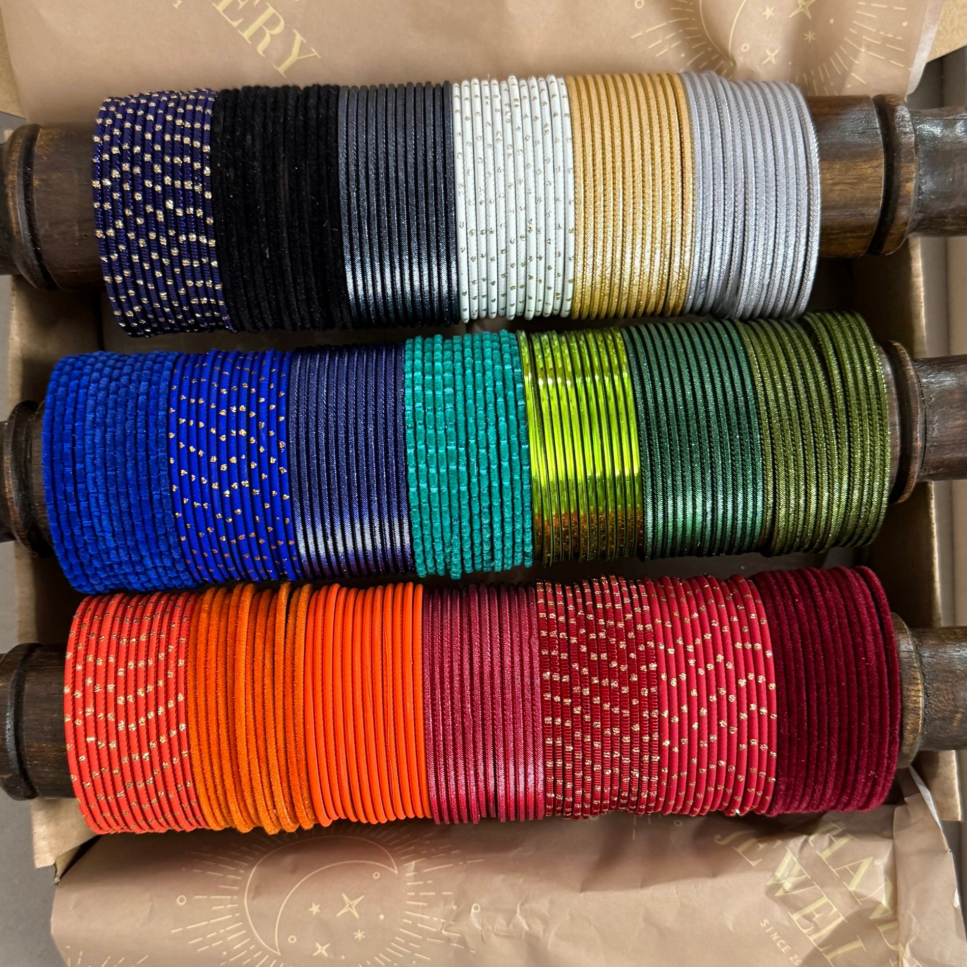 Colorful bangles on wooden bobbins with visible brand name.