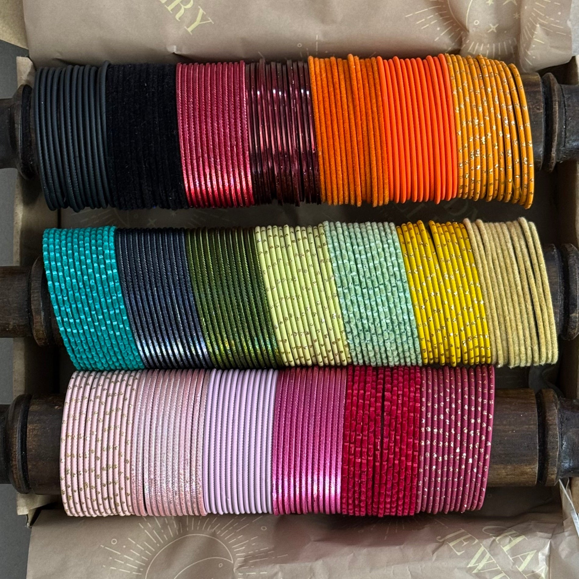 Colorful bangles on wooden spools in a box.