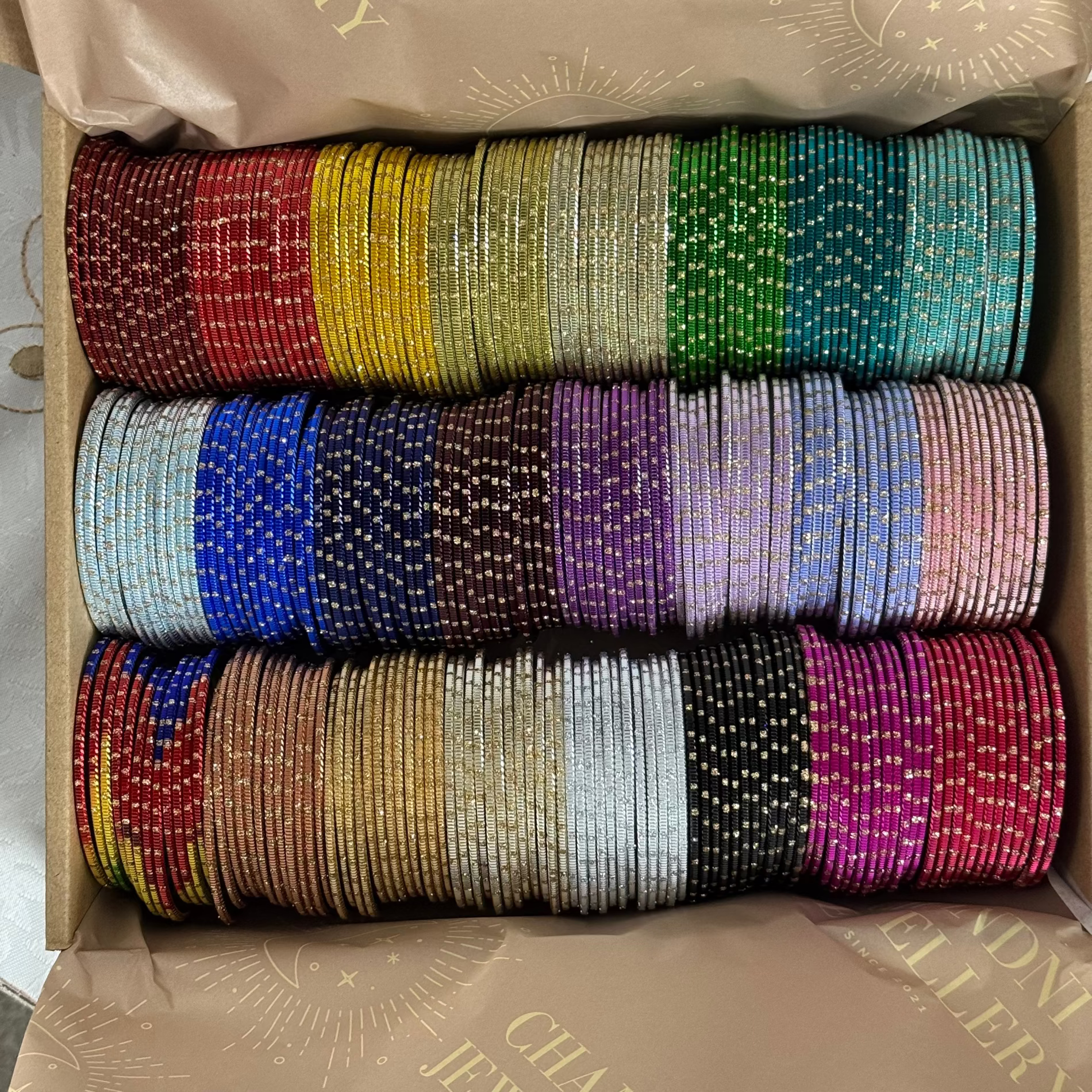 box filled with colorful metallic bangles in multiple shades.