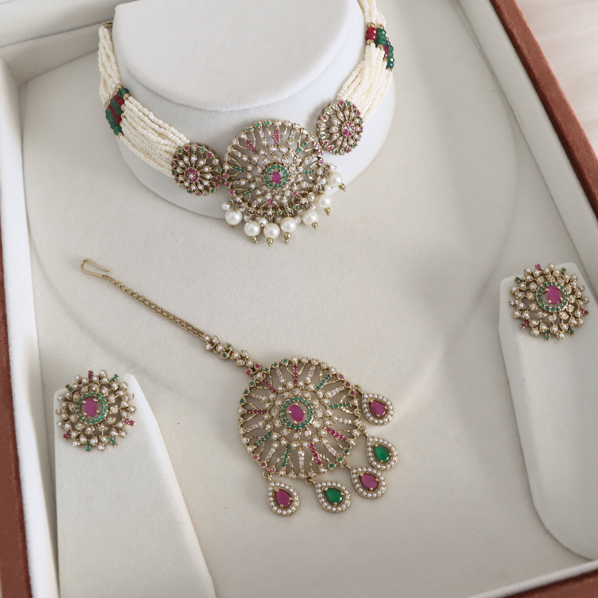 Jewelry set including necklace, earrings, and hairpin on a white stand.