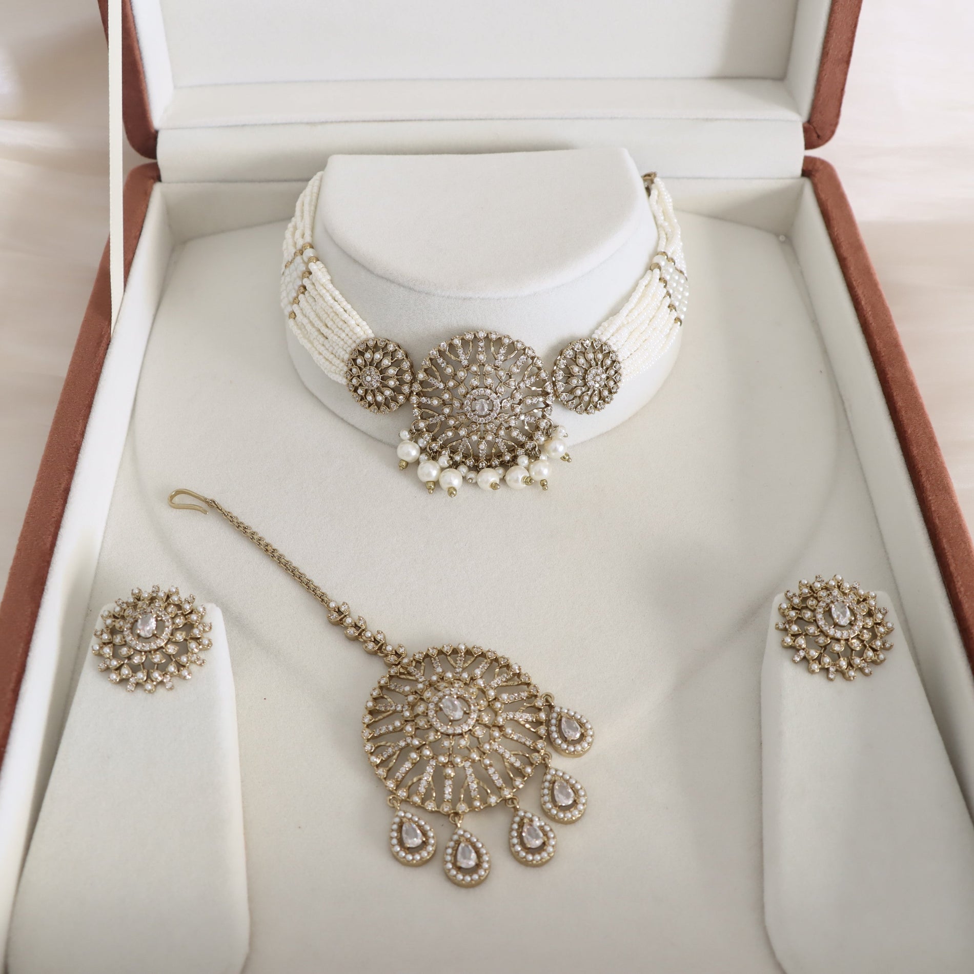 Jewelry set with necklace, earrings, and hairpin on a white stand in an open jewelry box.