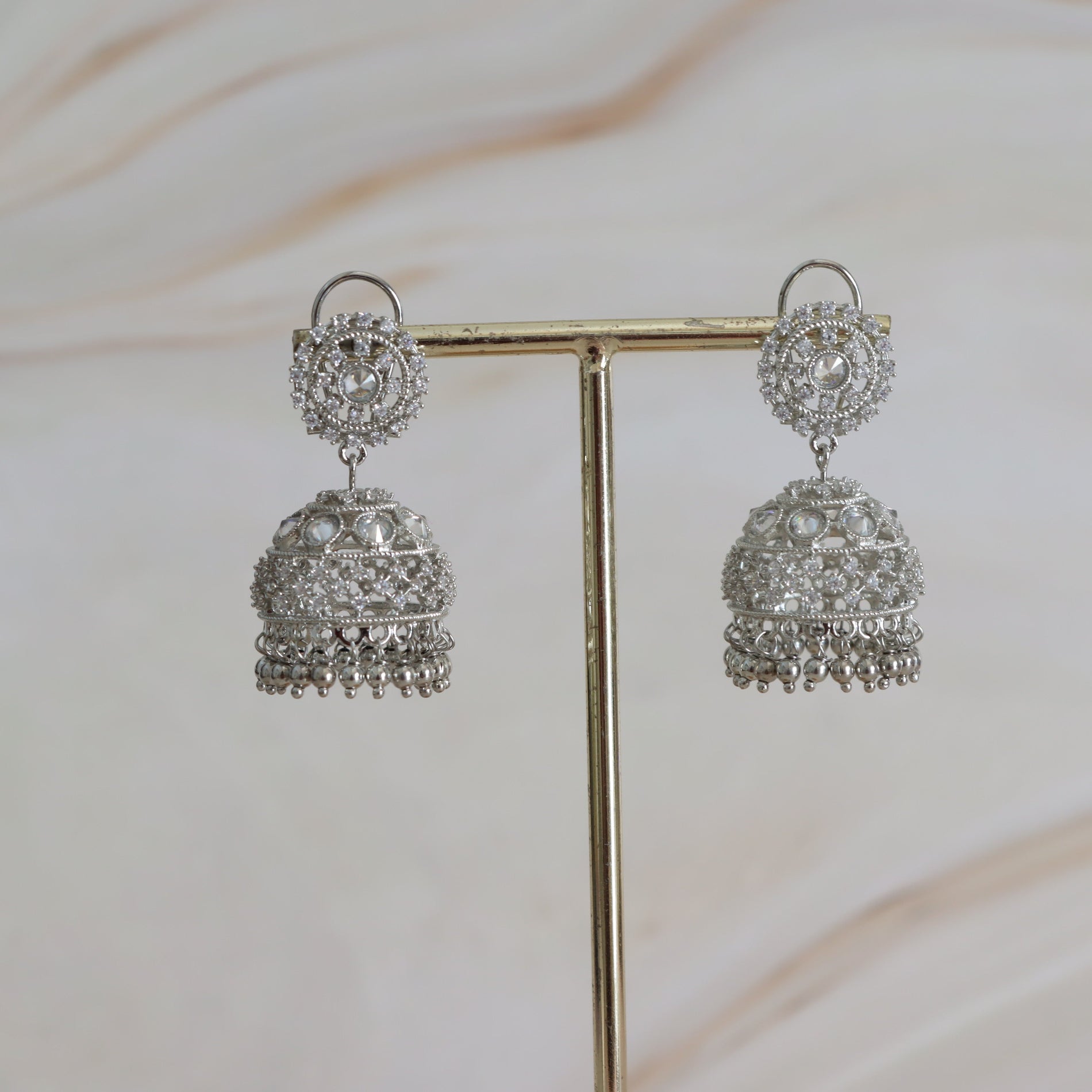 Pair of silver earrings on a stand with a soft background
