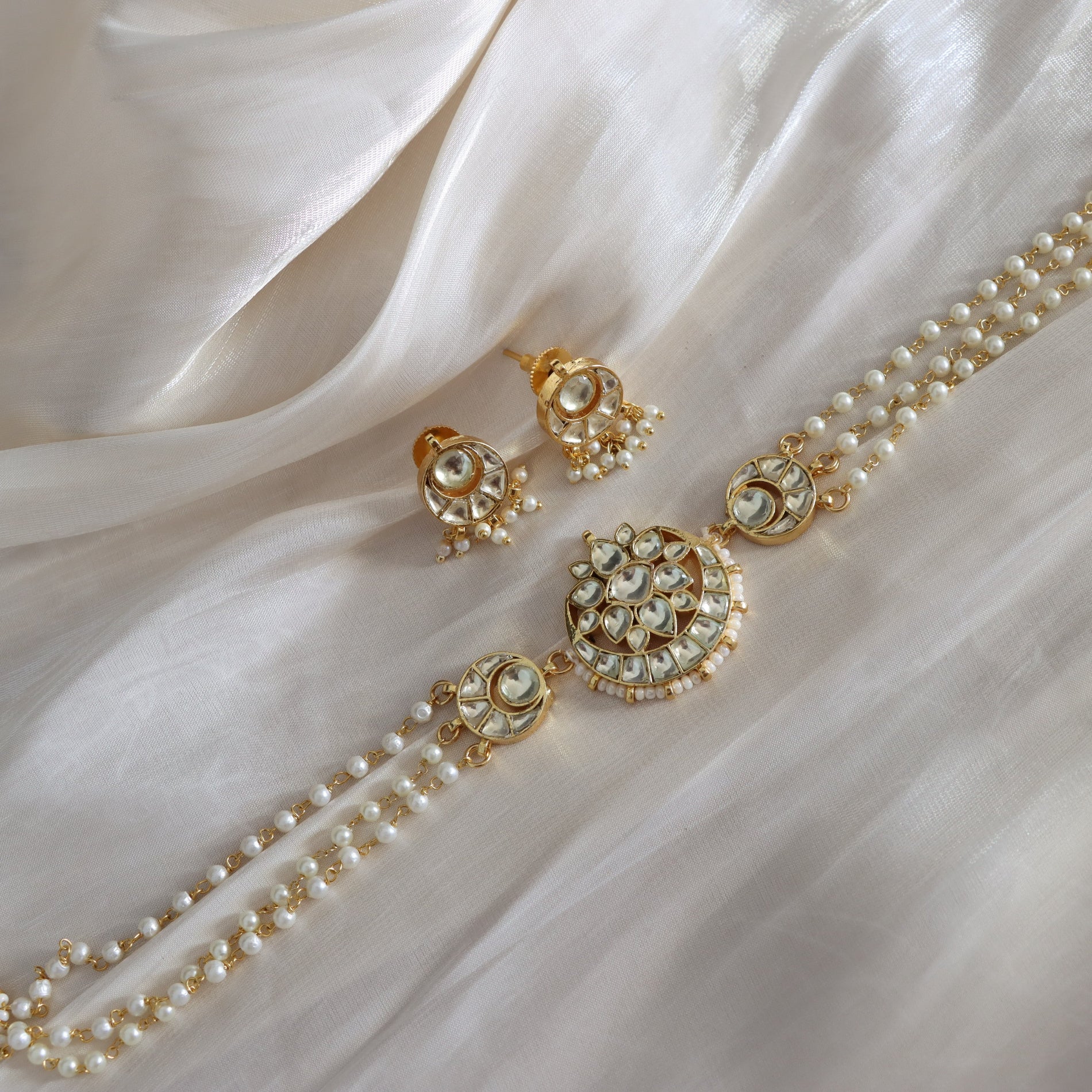 Pearl necklace and earrings on a white fabric background