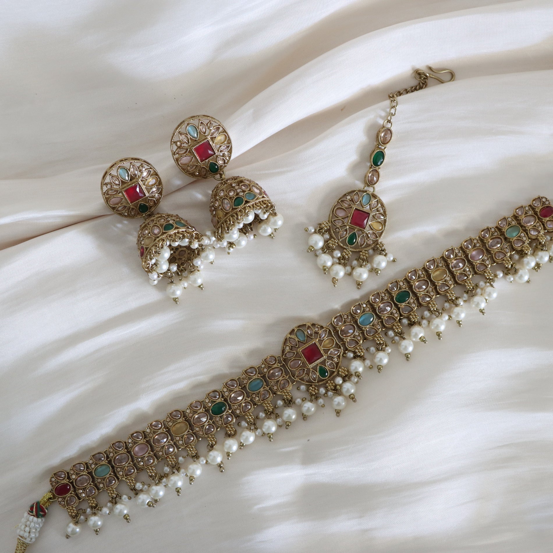 Ornate jewelry set with necklace, earrings, and bangles on a white fabric background