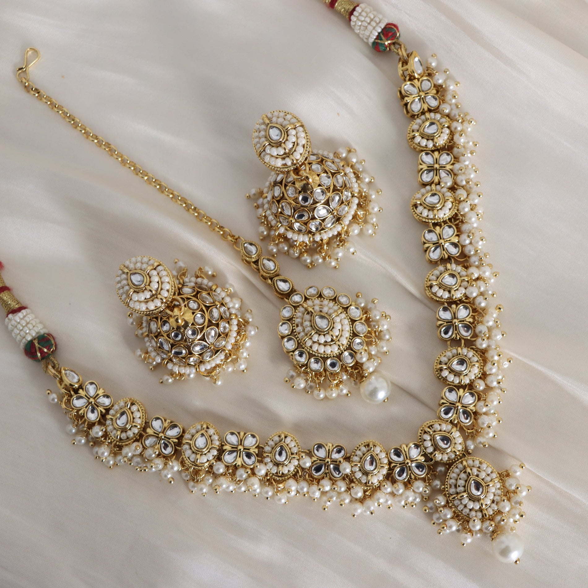 Ornate gold and pearl jewelry set on a white surface