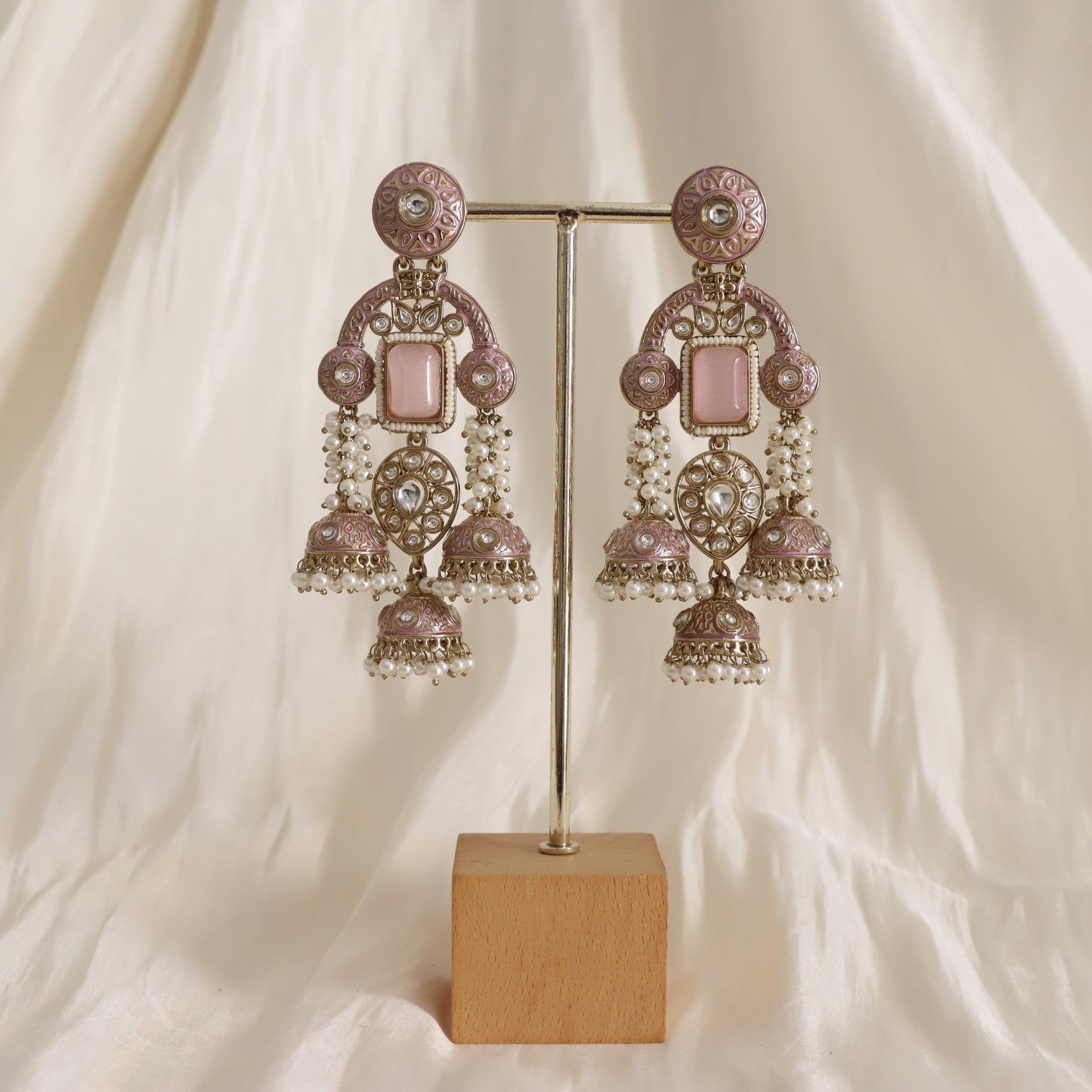 Ornate earrings on a stand with a soft beige background