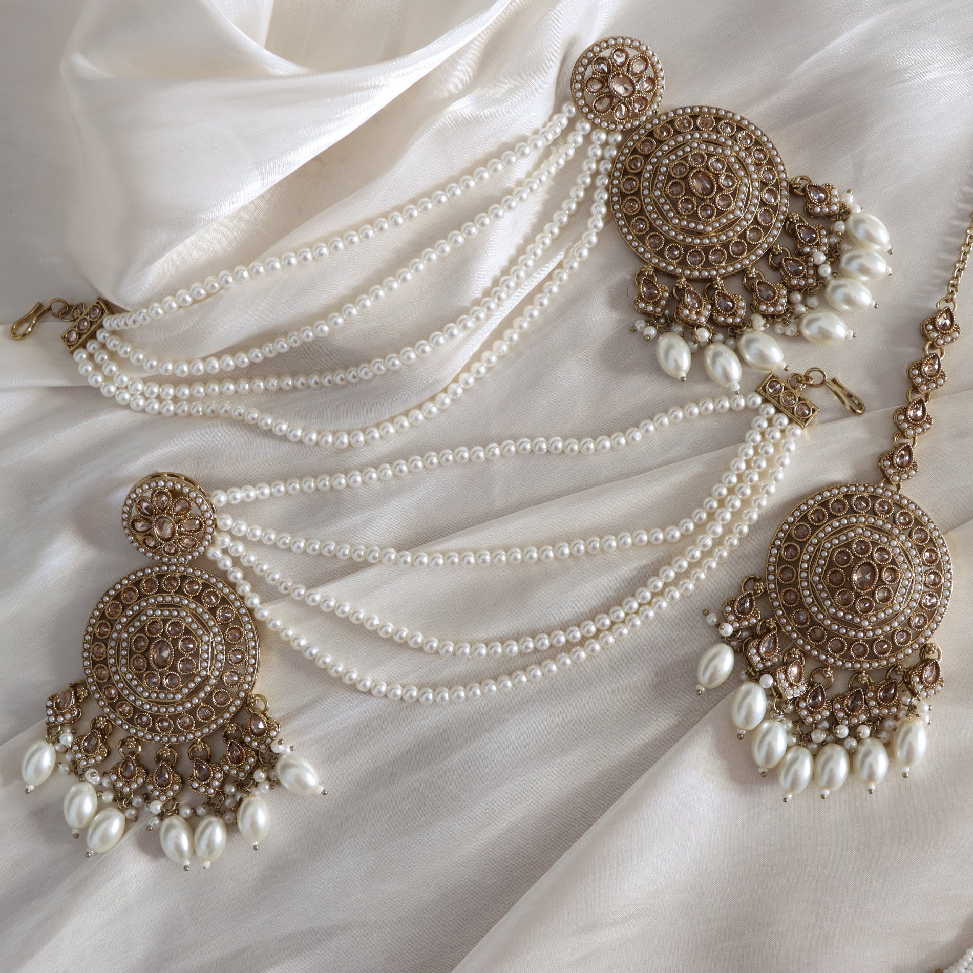 Pearl necklace with gold pendants on a white fabric background