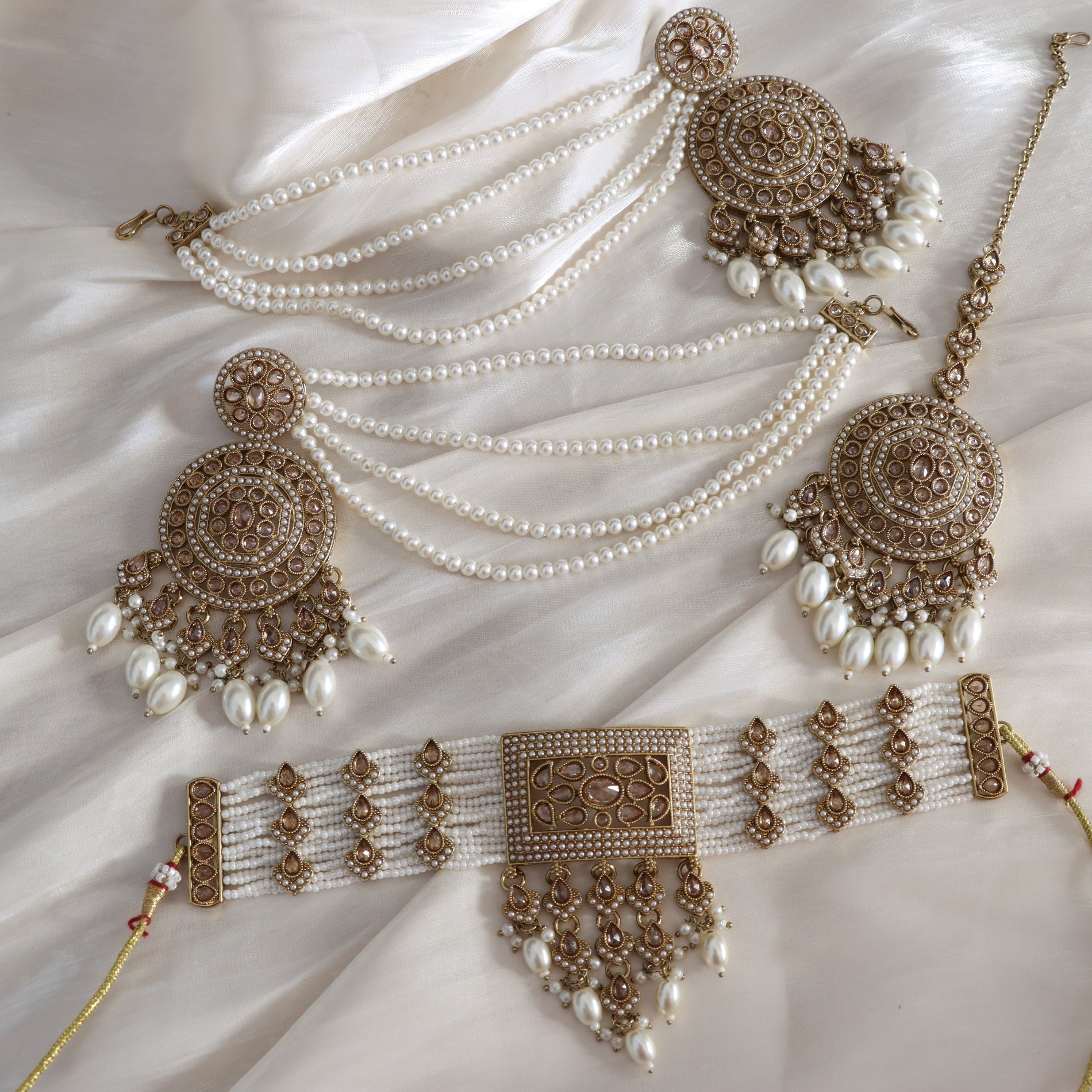 Ornate jewelry set with pearls on a soft fabric background
