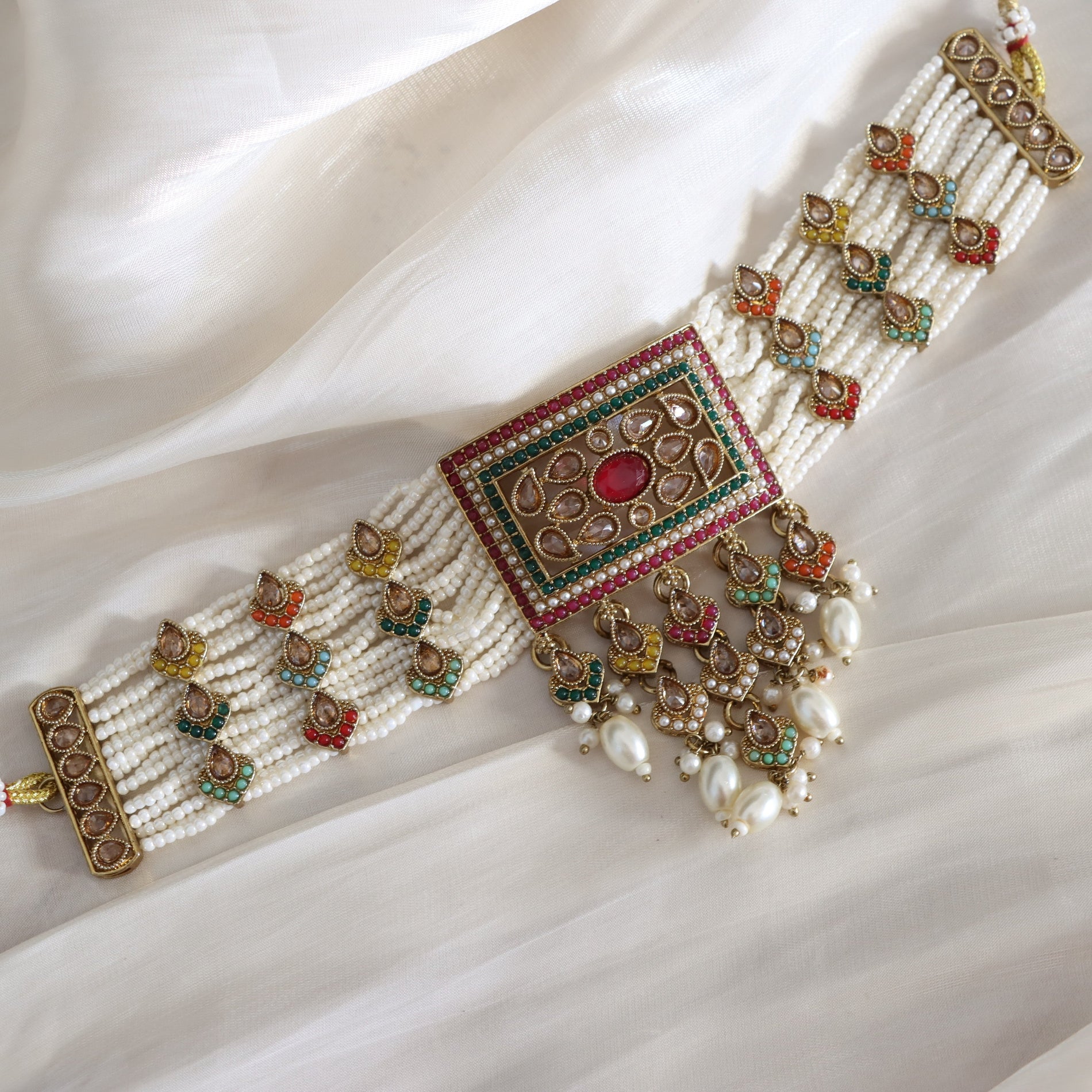 Decorative necklace with beads and gemstones on a white fabric background
