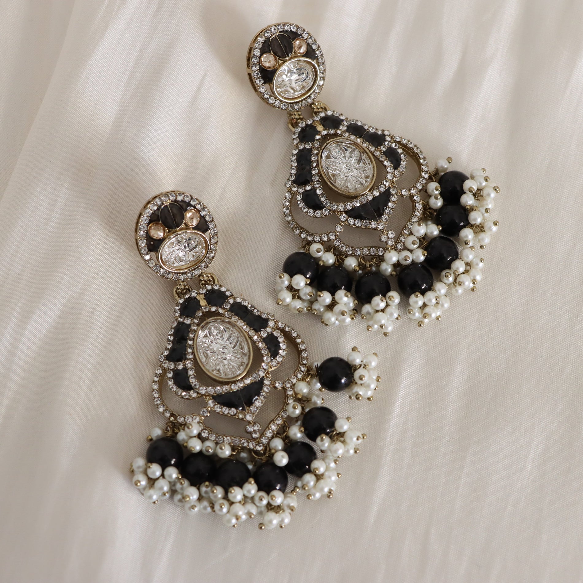 Ornate earrings with black and white stones on a light fabric background