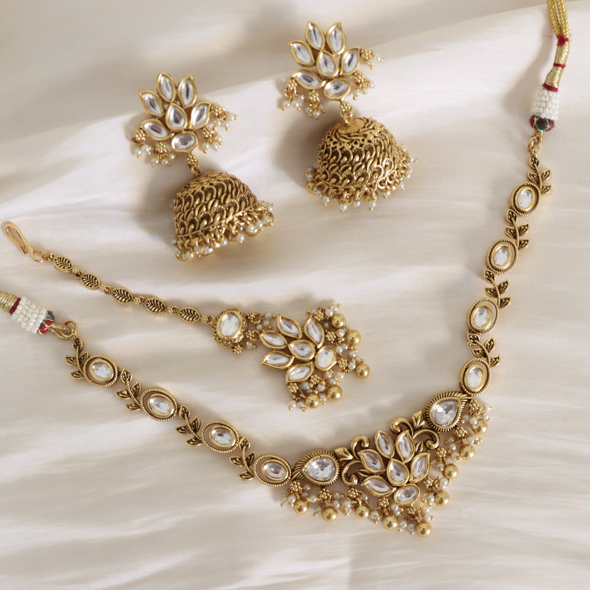 Gold necklace and earrings set on a white fabric background