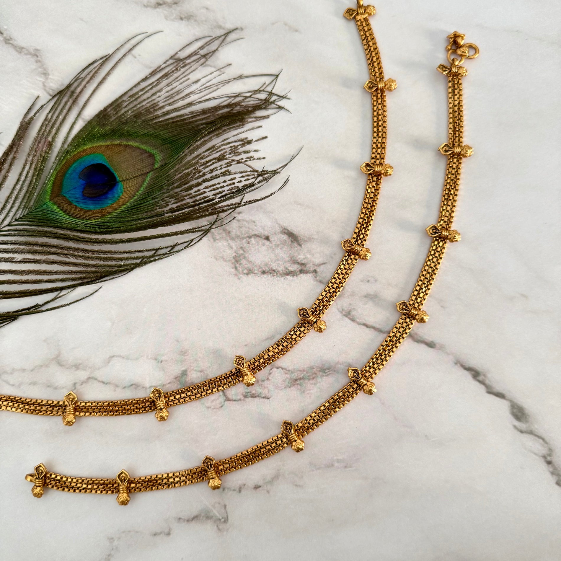 Gold anklet on a marble surface.