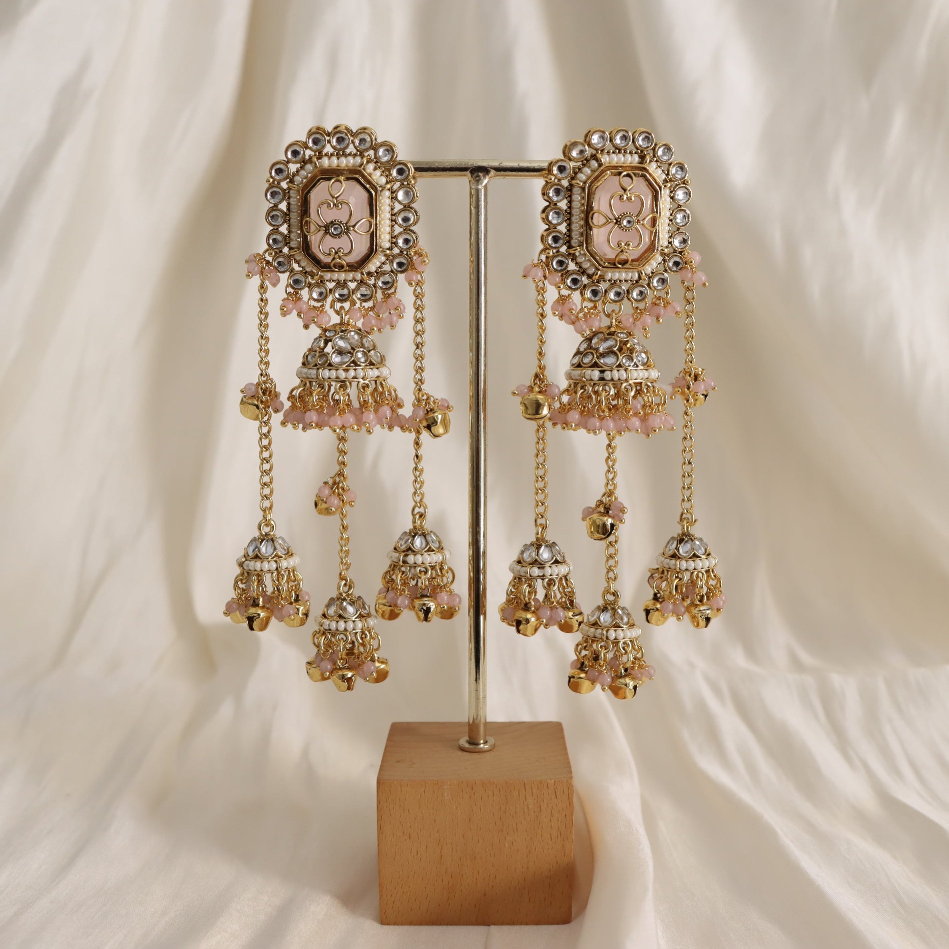 Ornate earrings on a stand with a soft white background