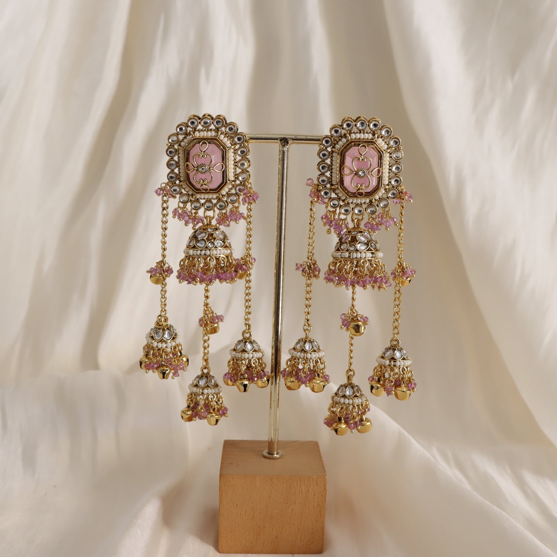 Ornate earrings with pink stones on a white fabric background