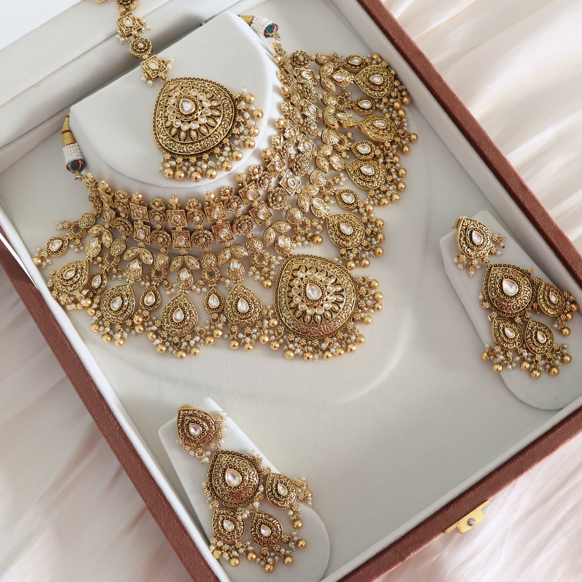 Gold jewelry set including necklace, earrings, and ring in a box