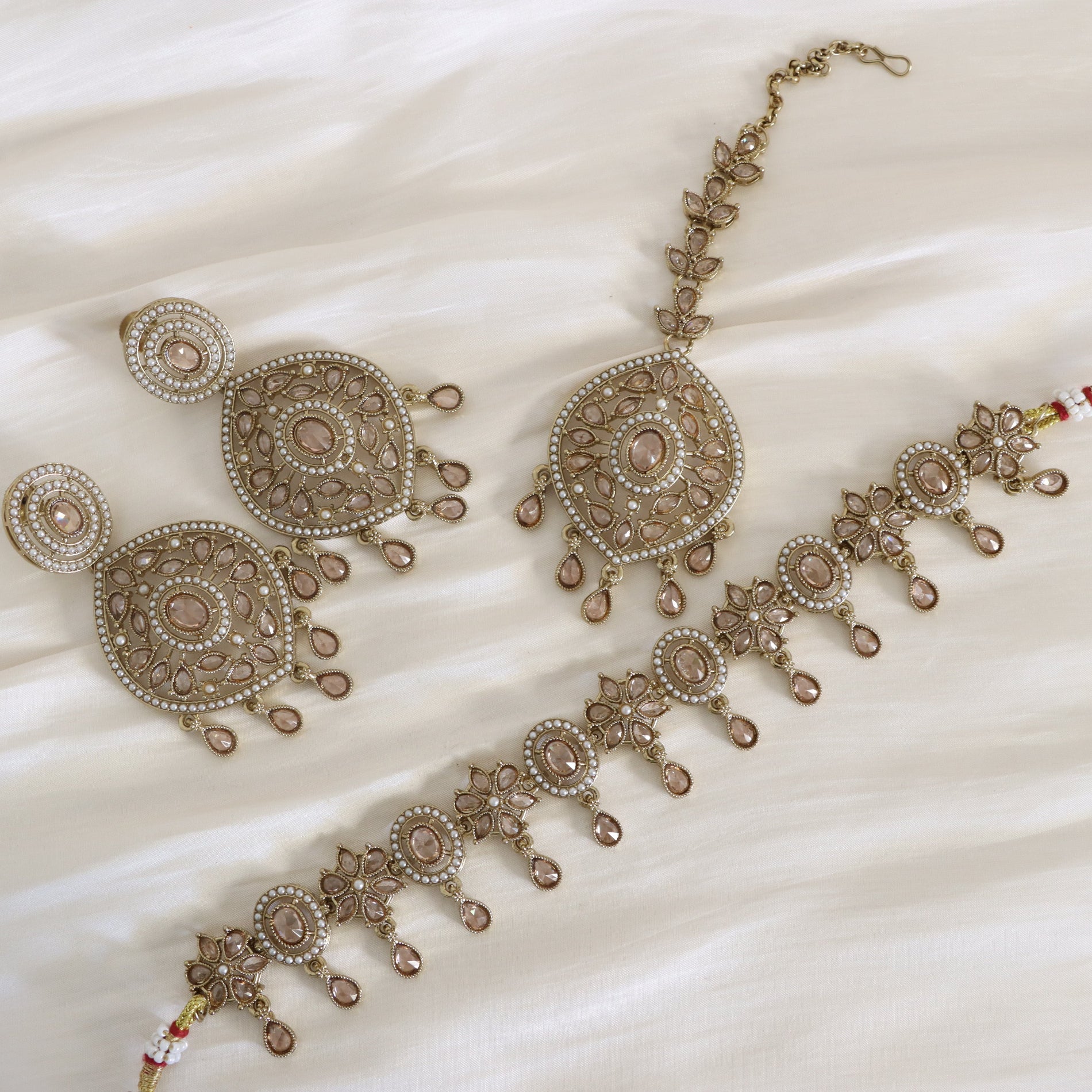 Ornate necklace and earrings set on a white fabric background