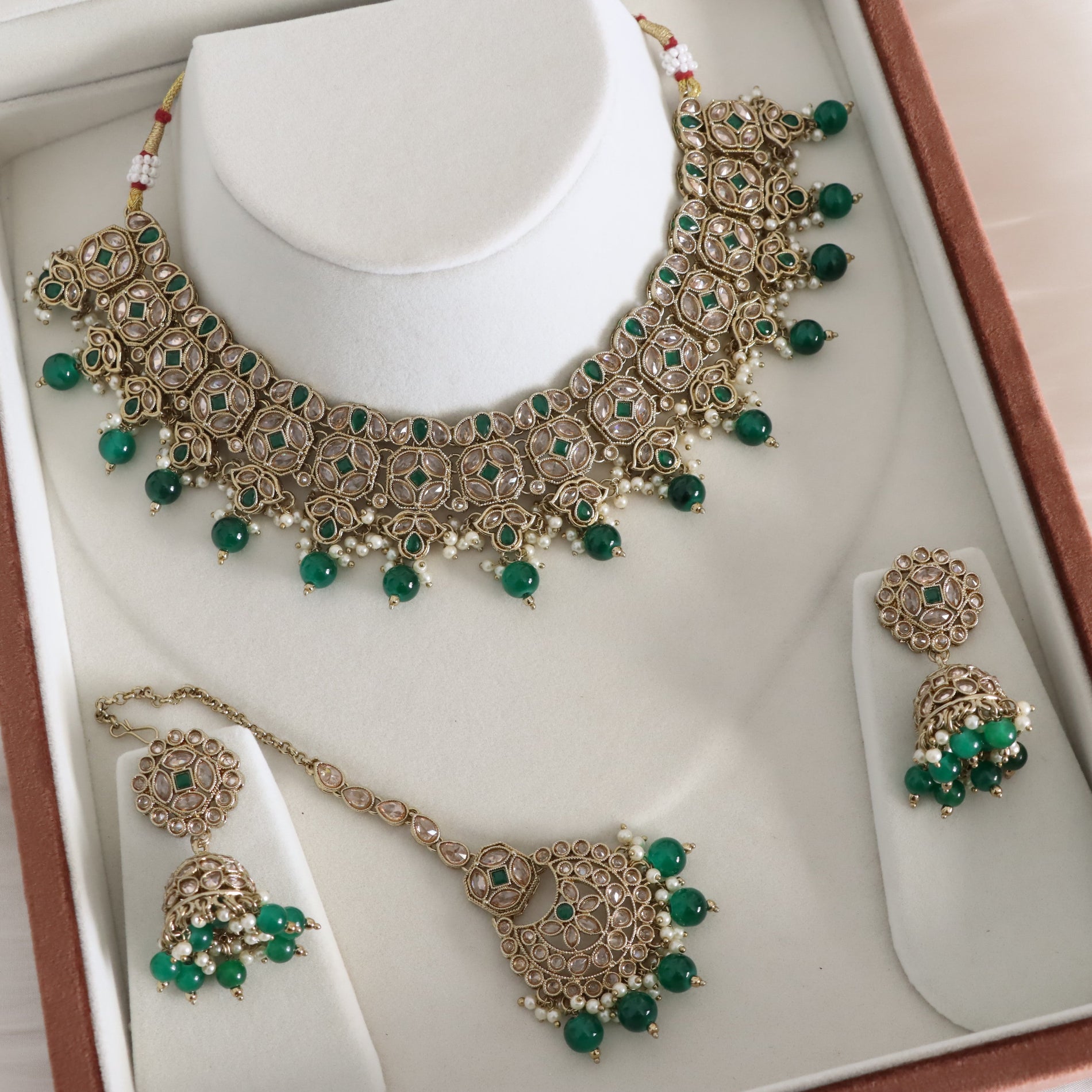 Jewelry set with necklace, earrings, and pendant on a white stand.