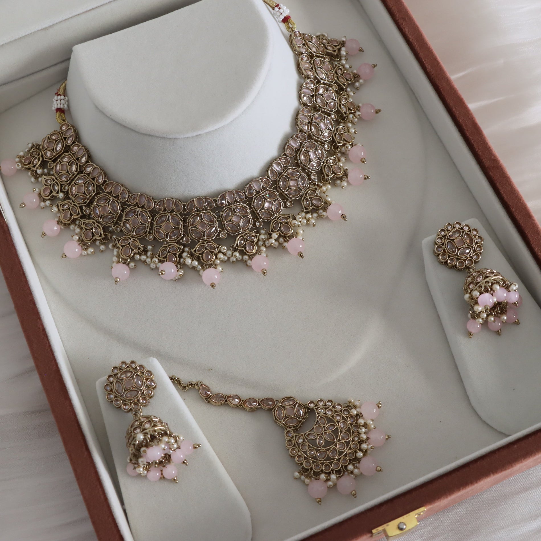 Gold necklace with pink beads and matching earrings in a jewelry box.