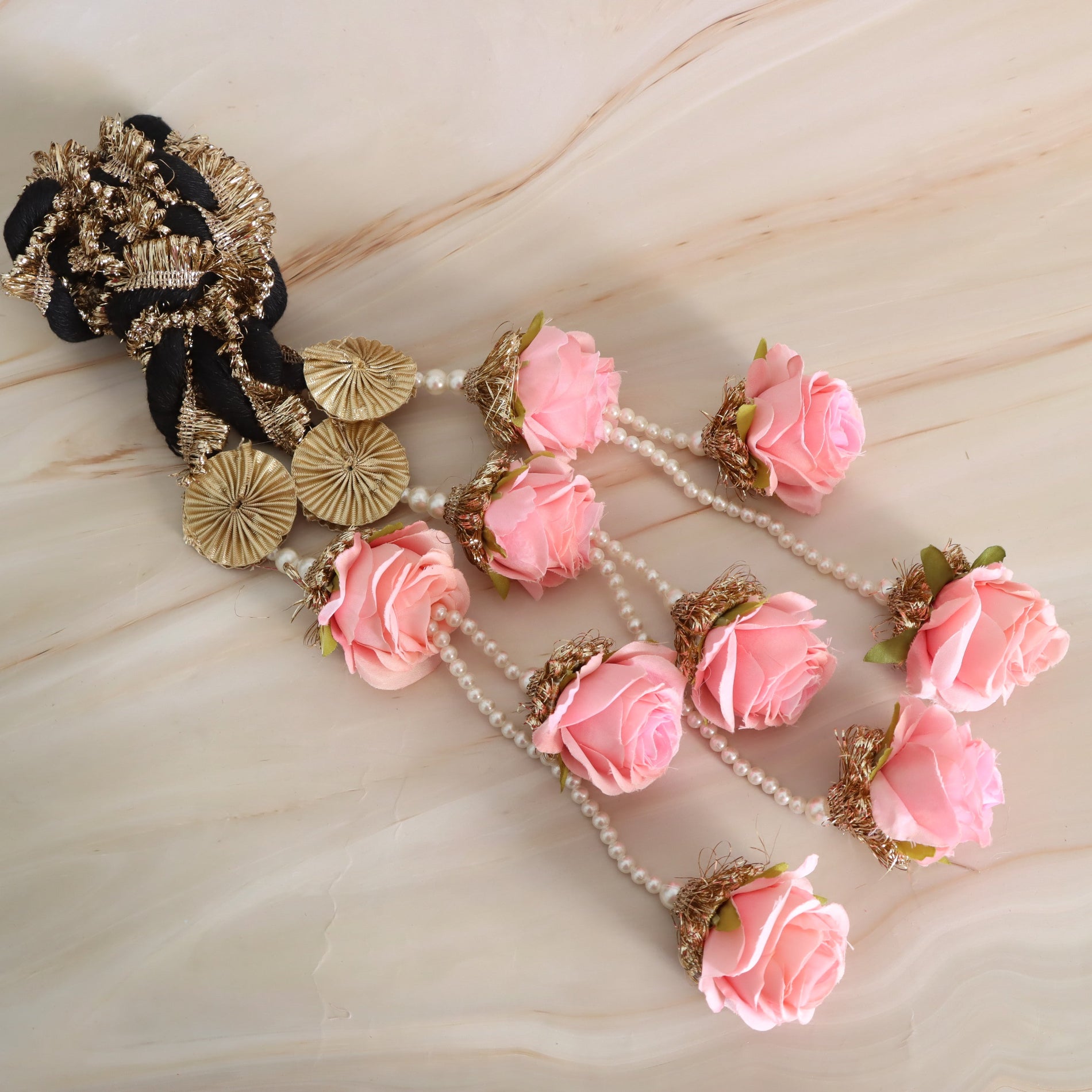 Decorative headband with pink flowers and gold accents on a beige surface