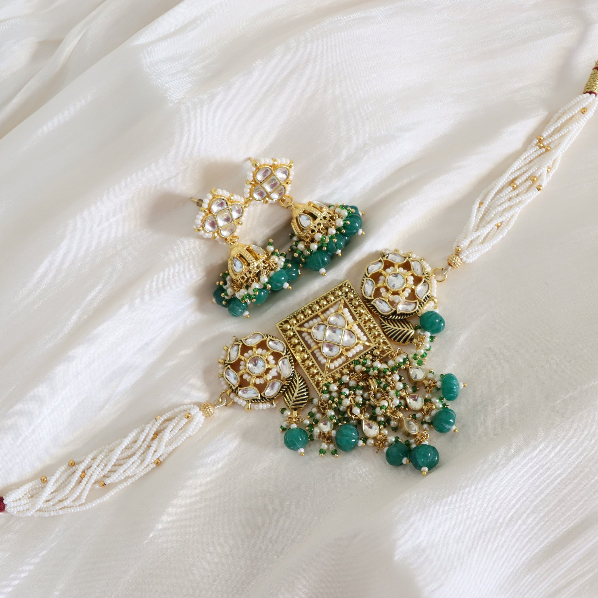 Ornate gold and green jewelry set on a white fabric background