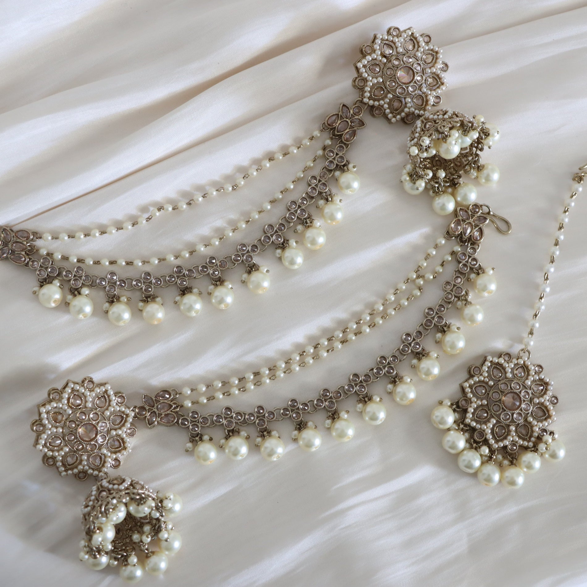 Pearl necklace with floral clasps on a white fabric background