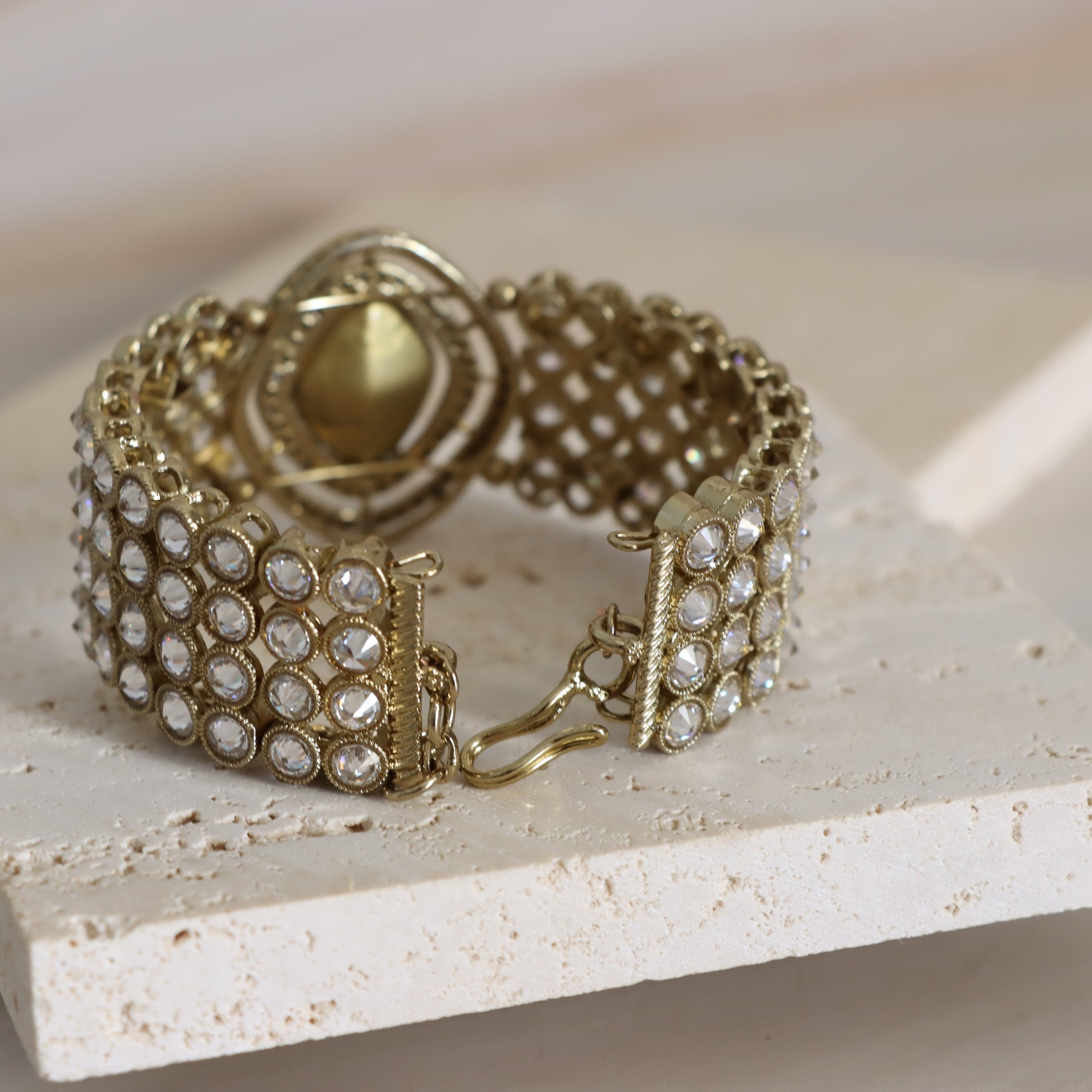 Gold bracelet with clear stones on a light surface