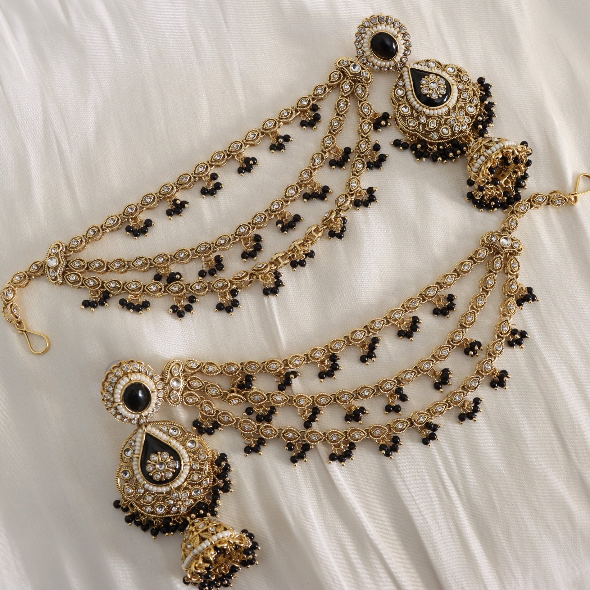 Decorative gold and black jewelry set on a white fabric background