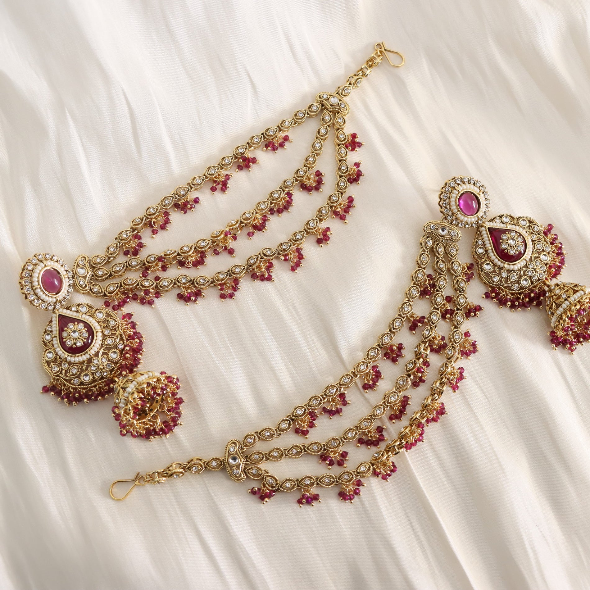 Gold and red gemstone jewelry set on a white fabric background