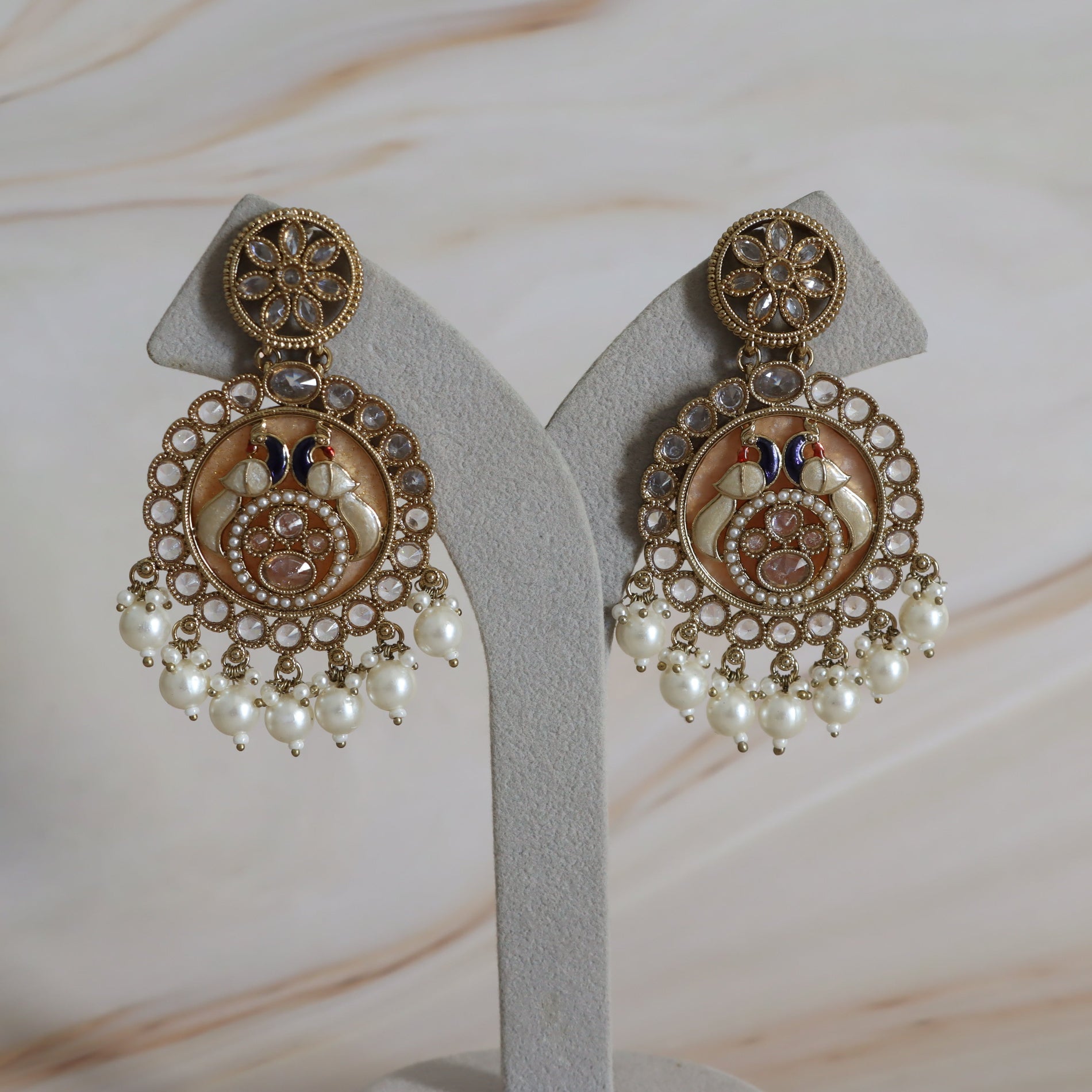 Ornate earrings with pearl-like beads on a neutral background