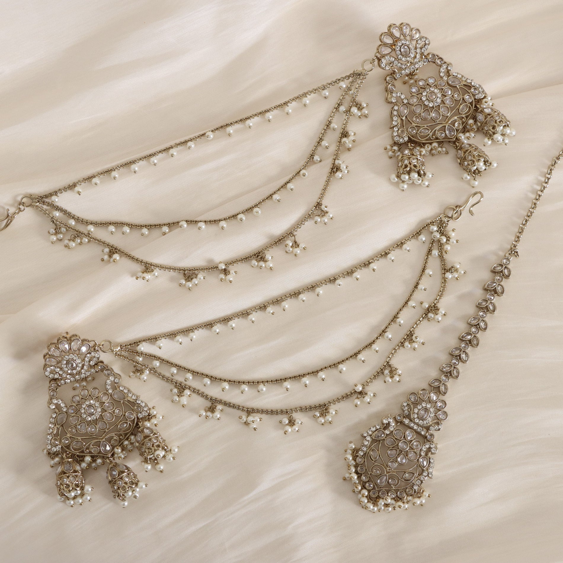 Ornate silver jewelry set with pendants on a beige fabric background