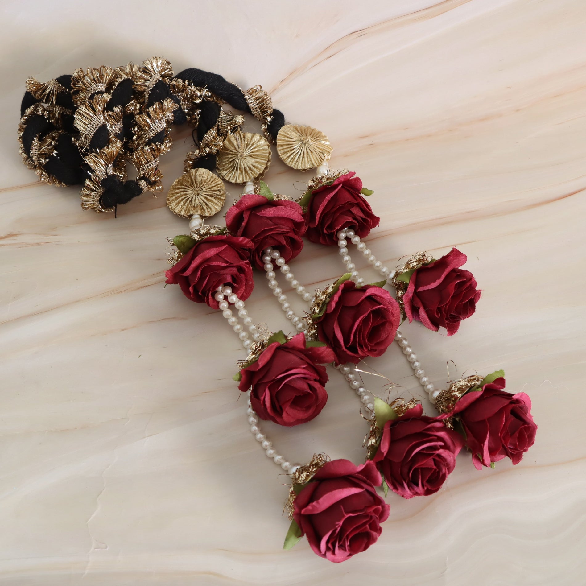 Decorative hair accessory with red roses and pearl strands on a beige background