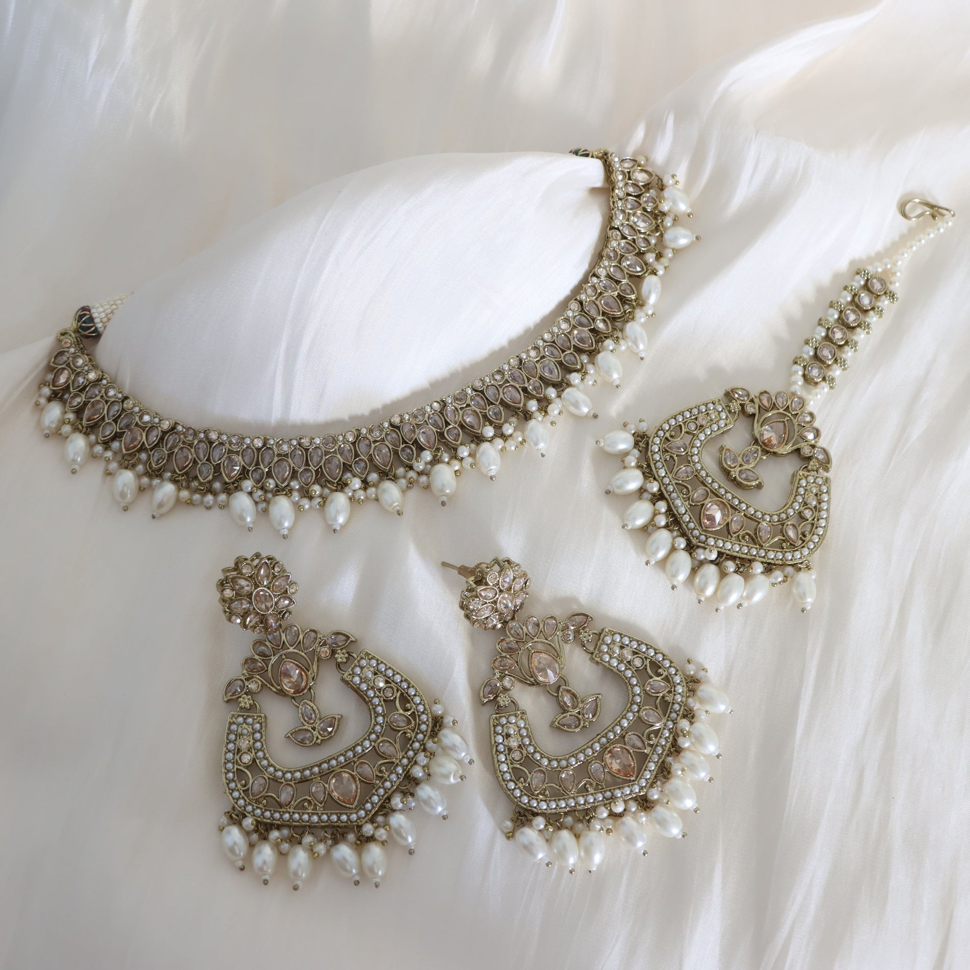 Ornate necklace and earrings set on a white fabric background