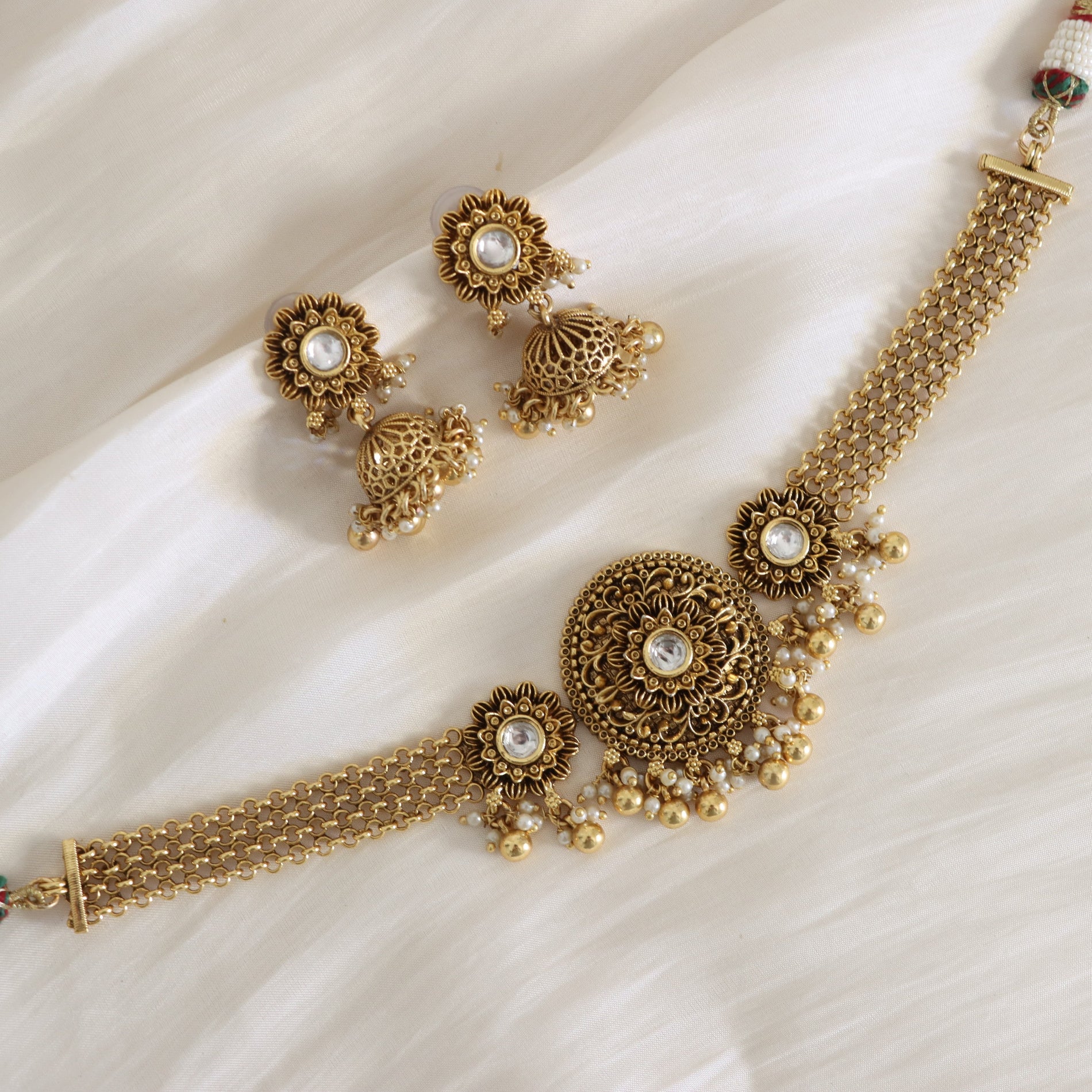 Gold jewelry set with necklace and earrings on a white fabric background