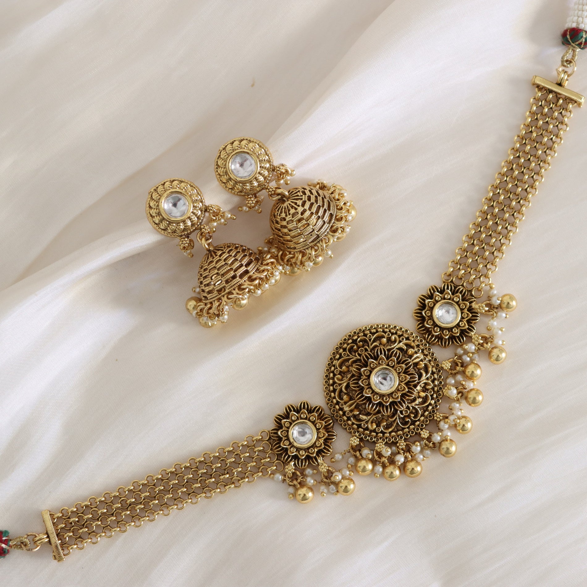 Gold necklace and earrings set on a white fabric background