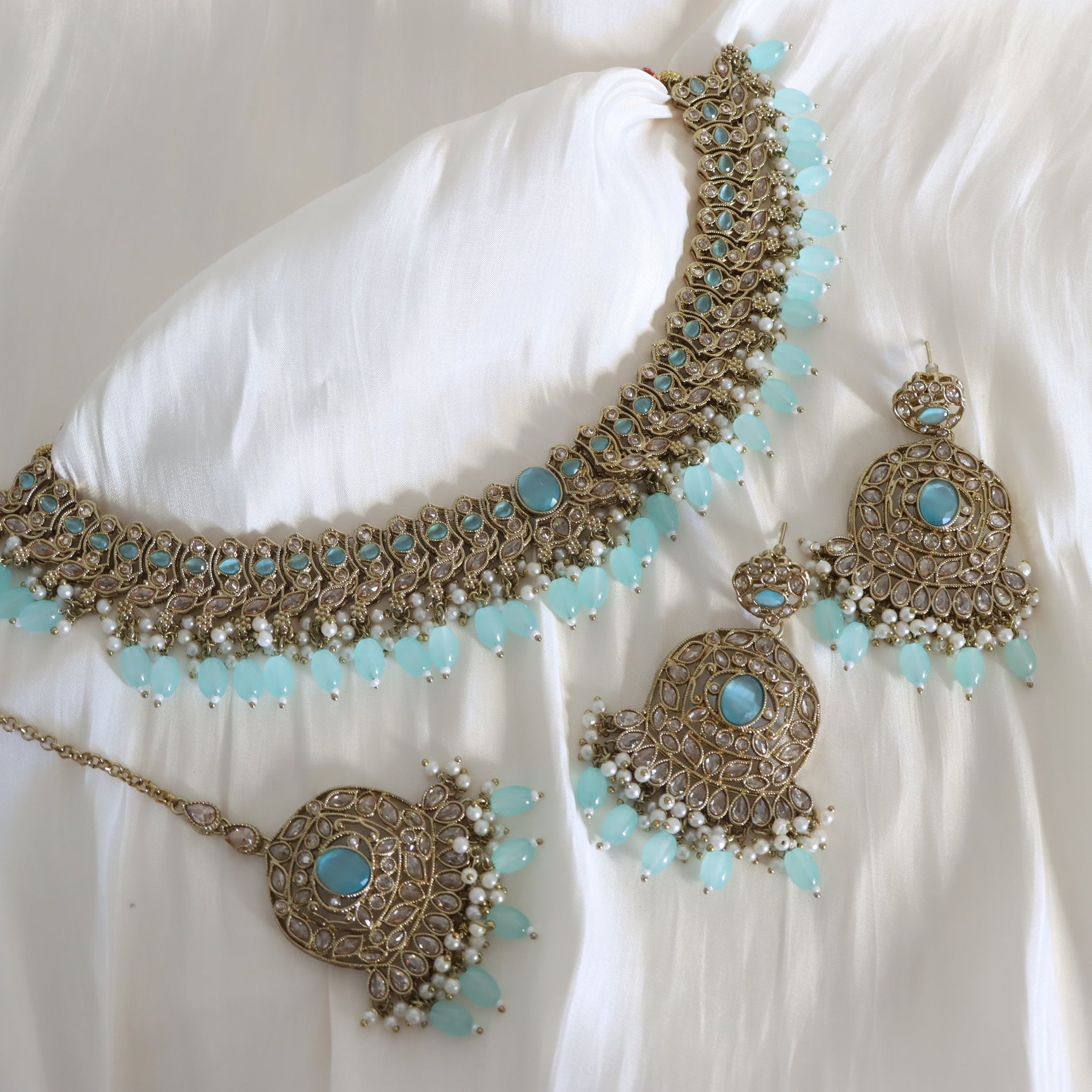 Ornate jewelry set with turquoise stones on a white fabric background