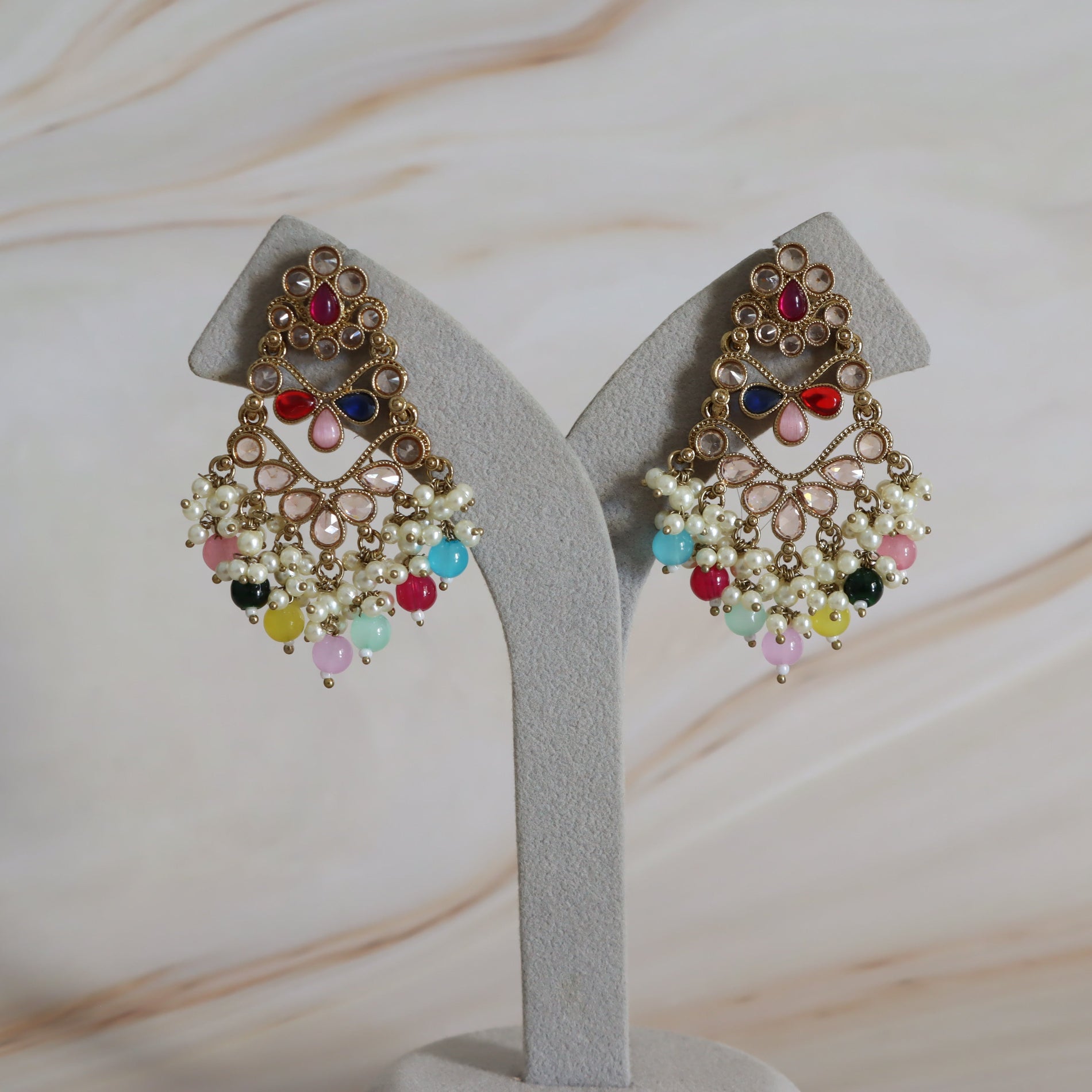 Pair of colorful earrings on a gray stand with a light background