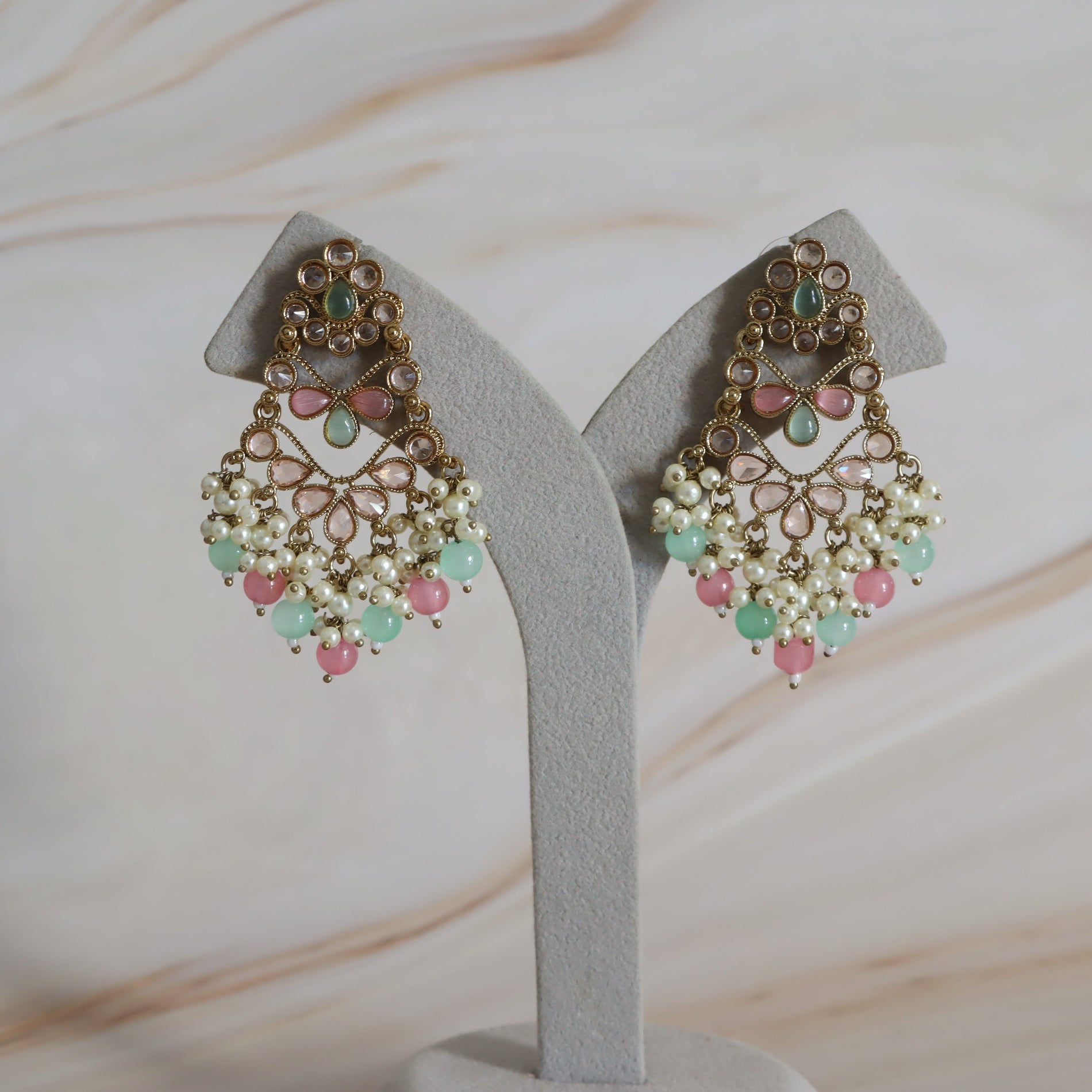 Pair of ornate earrings on a gray stand with a soft background