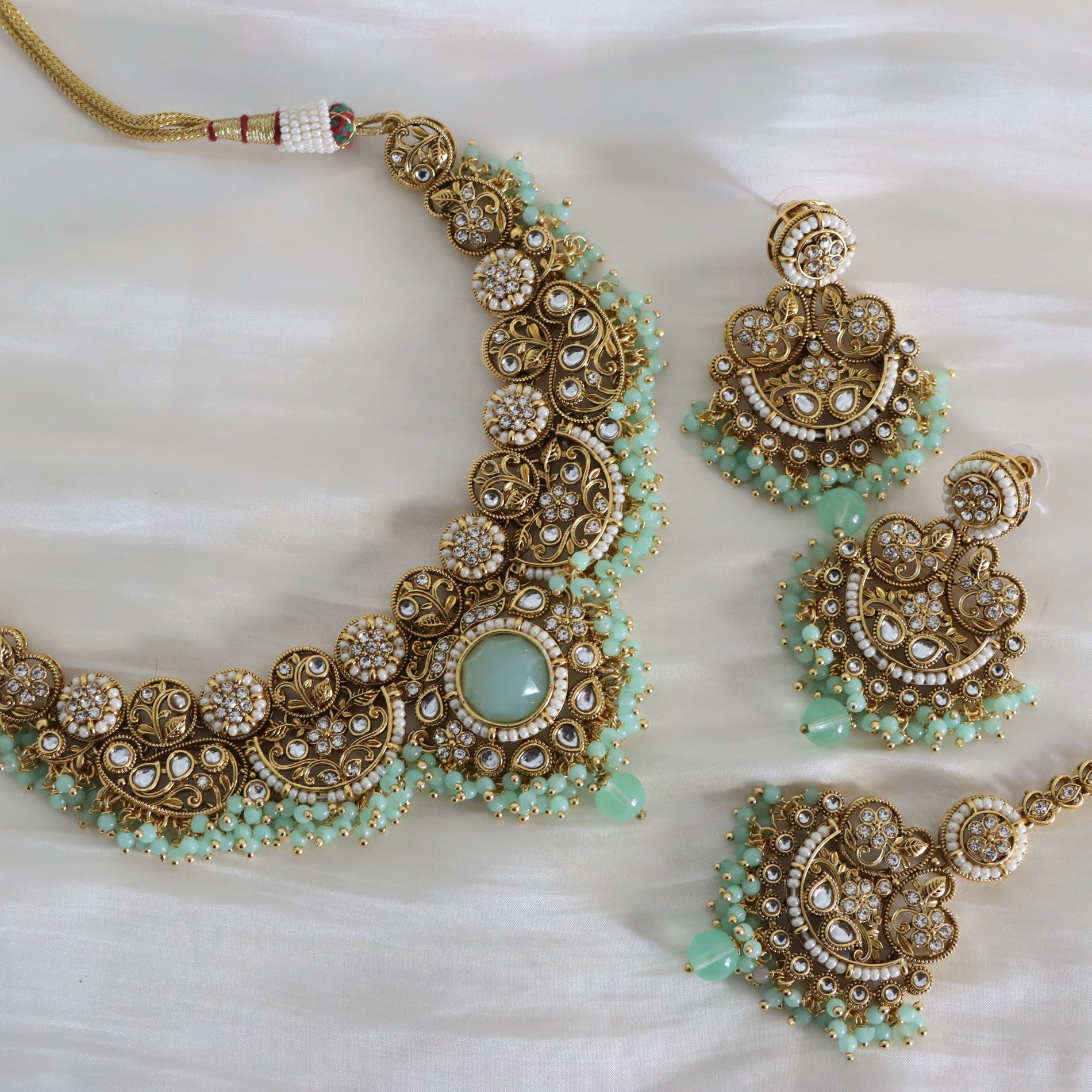 Ornate gold and turquoise necklace with matching earrings on a white background