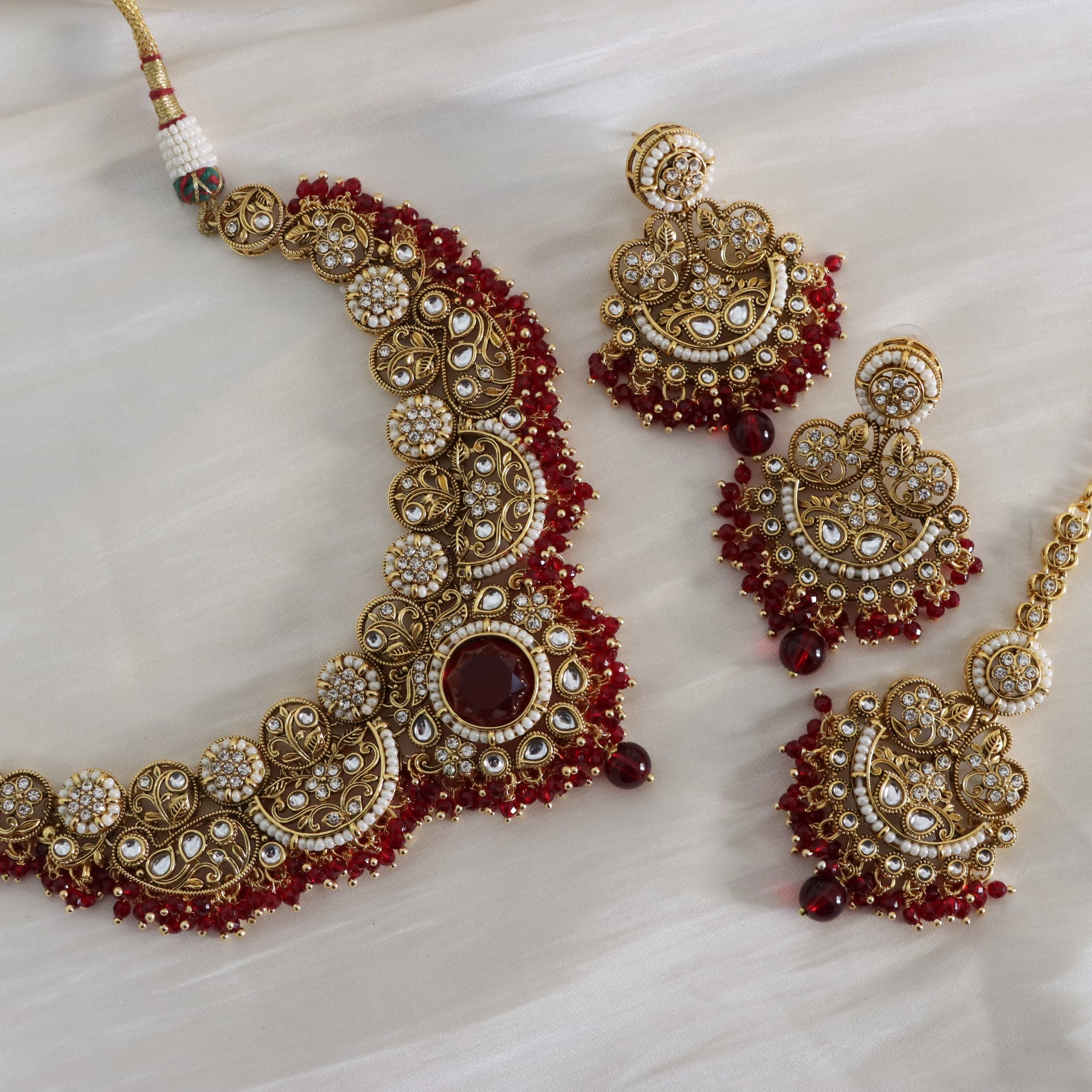 Ornate gold and red jewelry set on a white fabric background