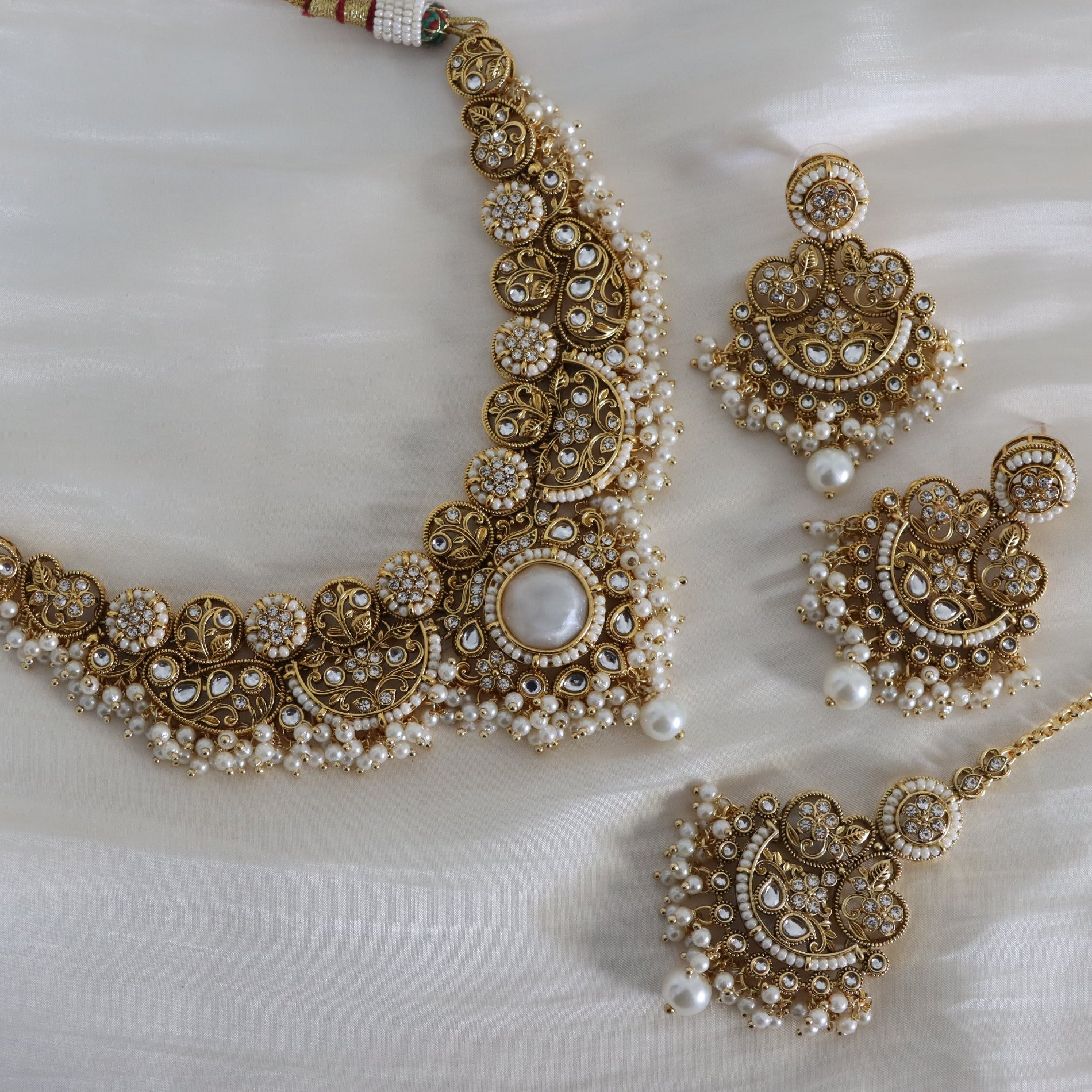 Gold and pearl jewelry set on a white fabric background