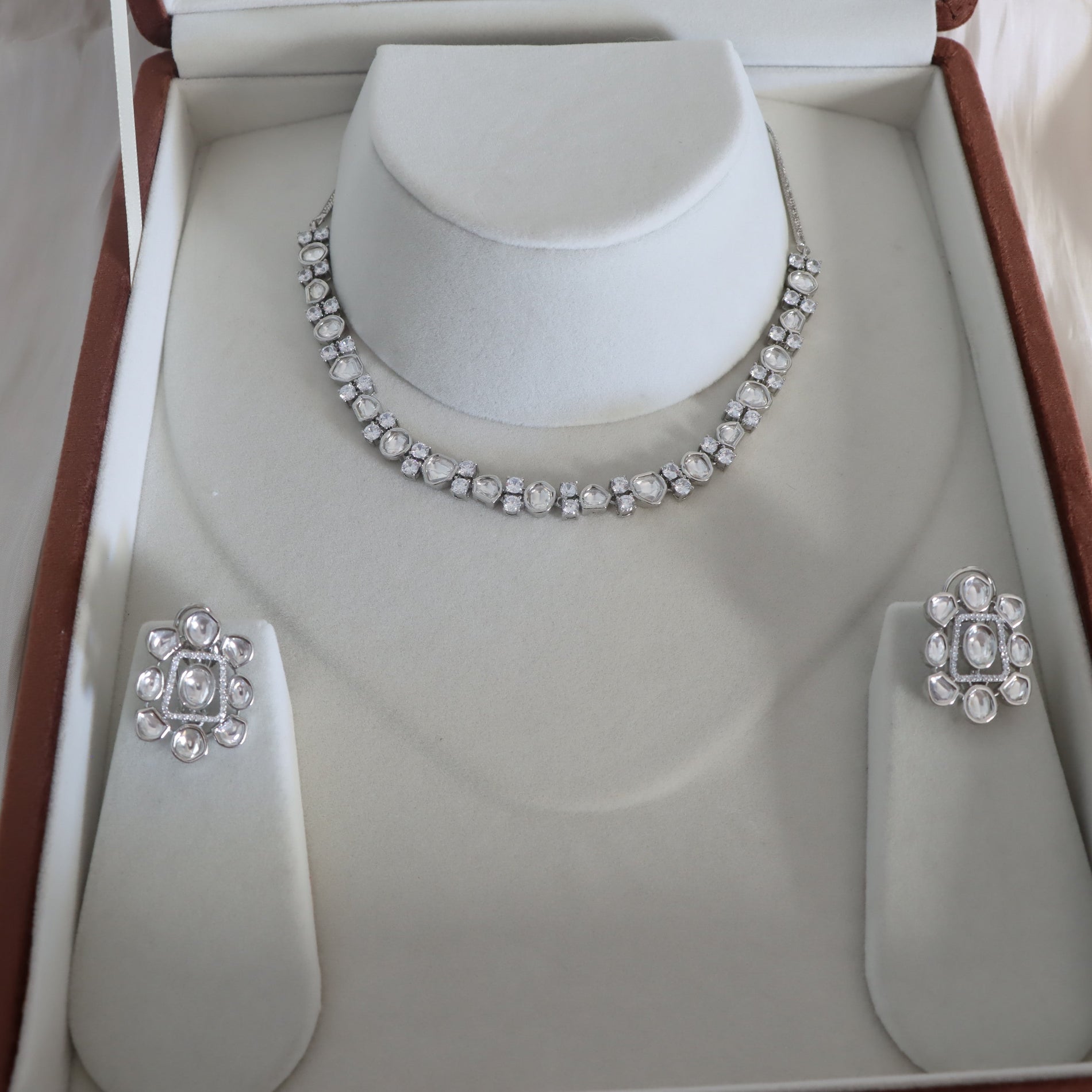 Silver necklace and earrings set on a mannequin bust in an open jewelry box.