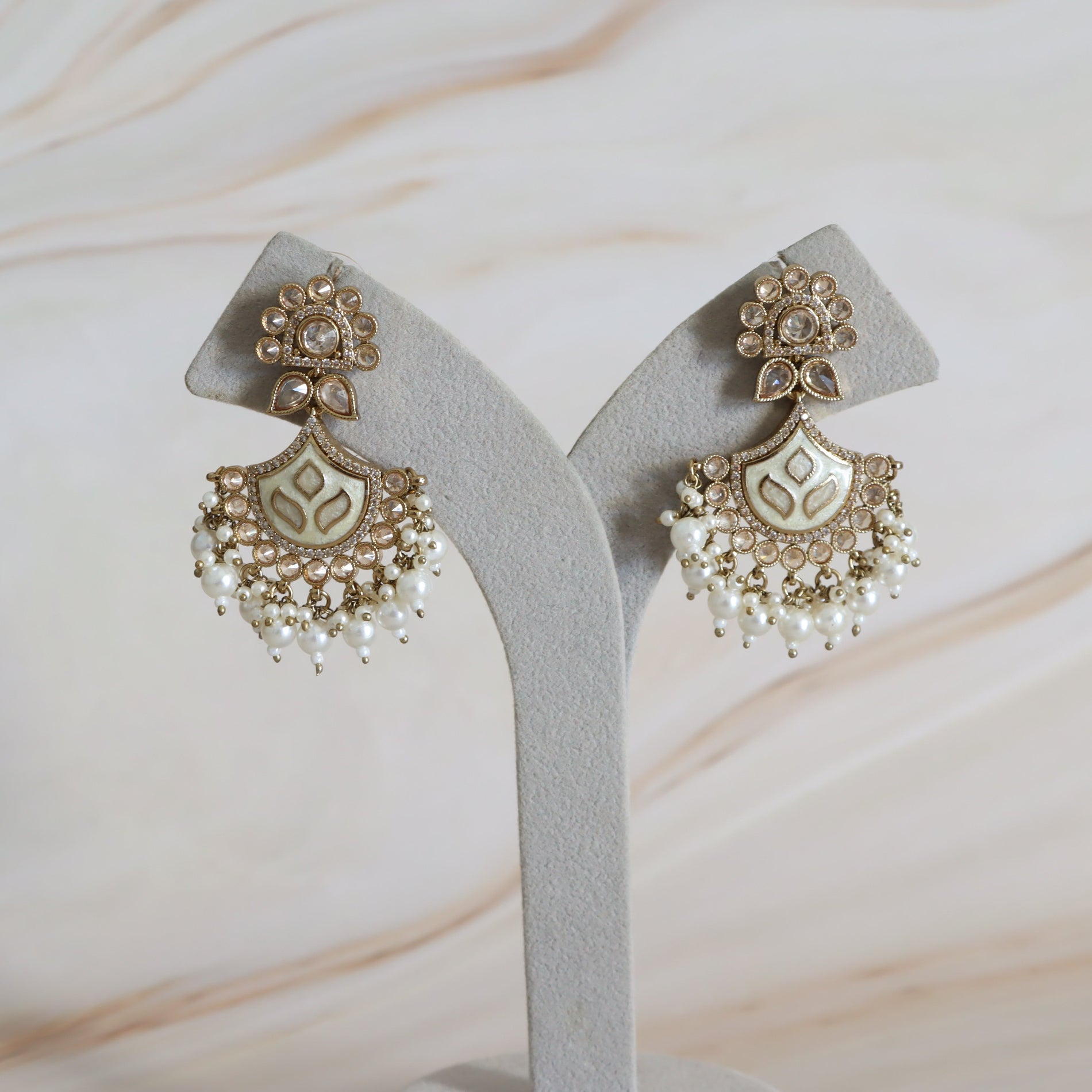 Decorative earrings on a gray stand with a marble background
