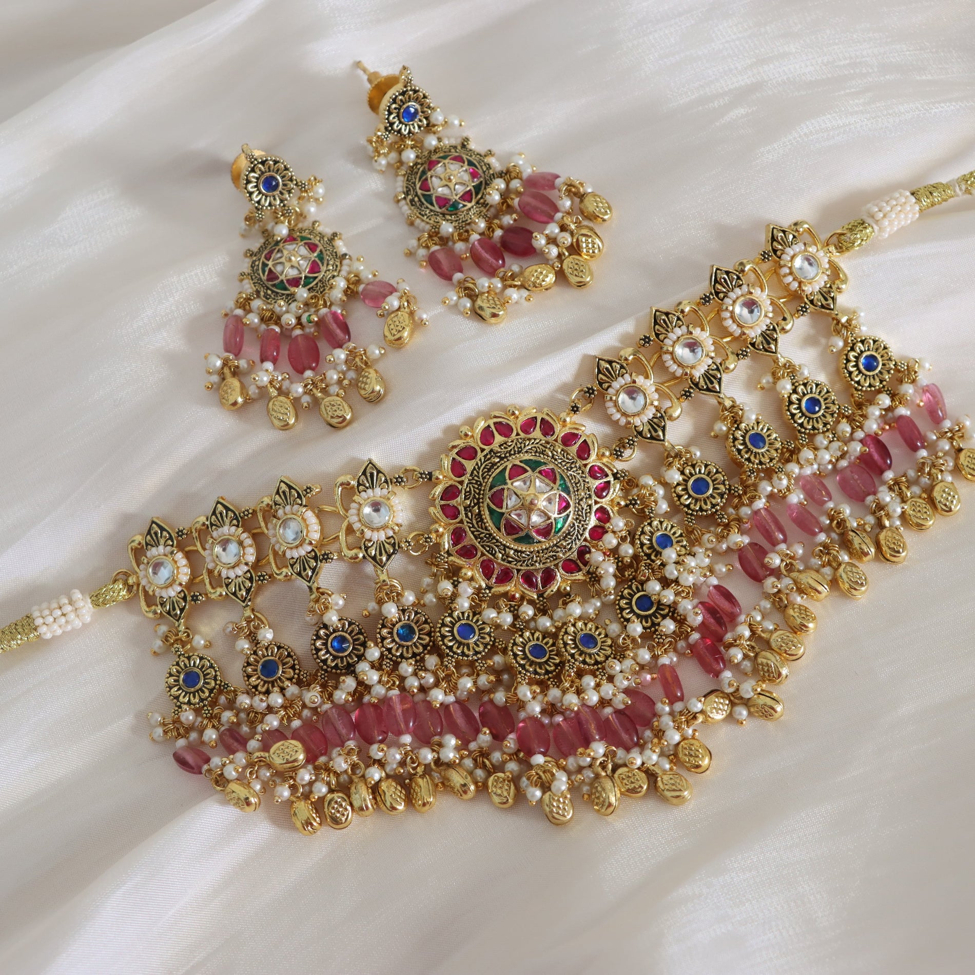 Ornate gold, red, and blue jewelry set on a white fabric background