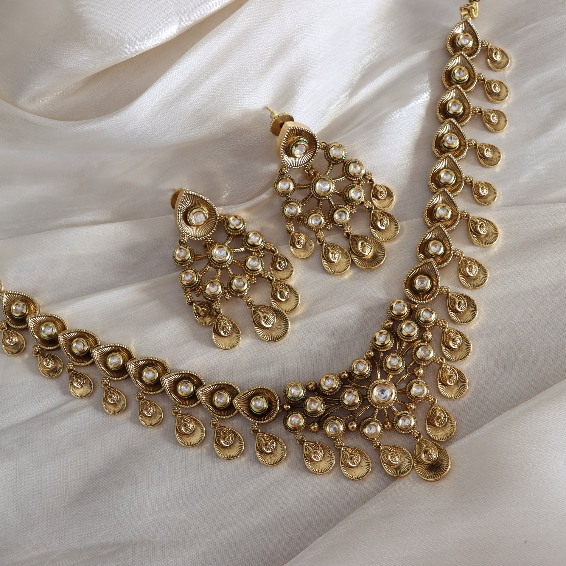 Gold necklace and earrings on a white fabric background