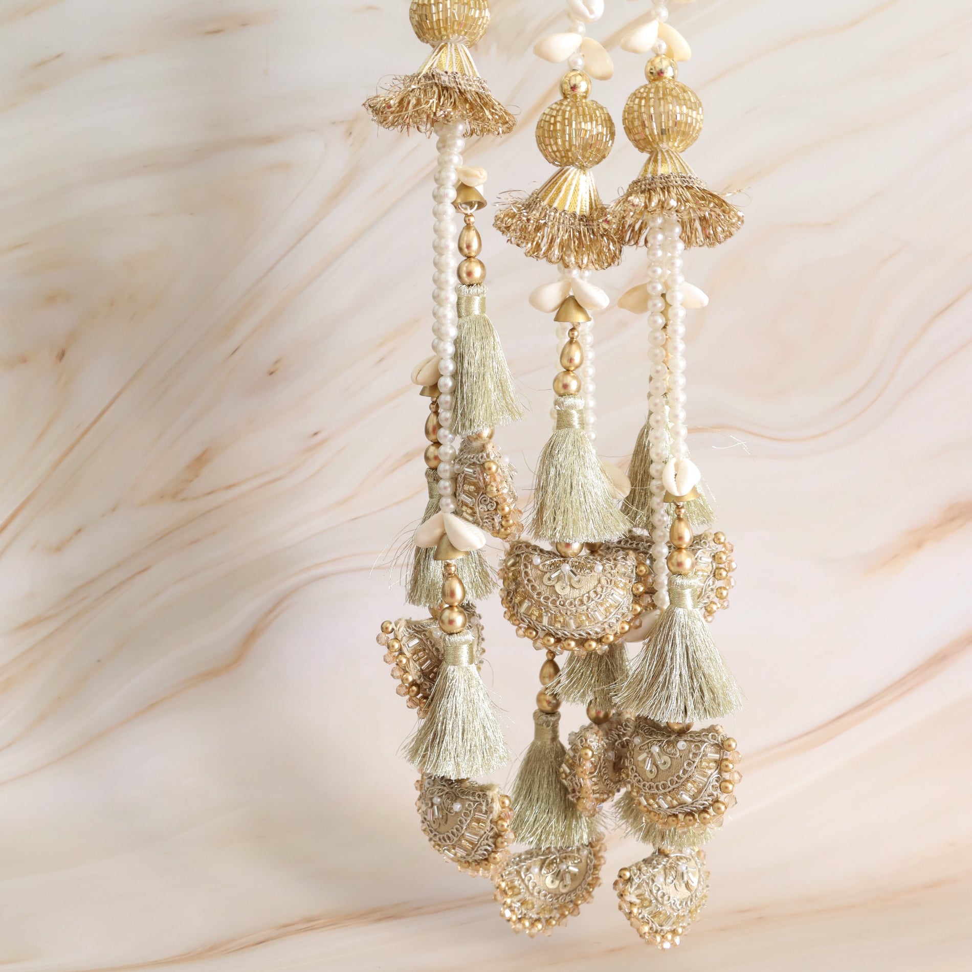Decorative hair accessory with gold and green tassels on a soft beige background